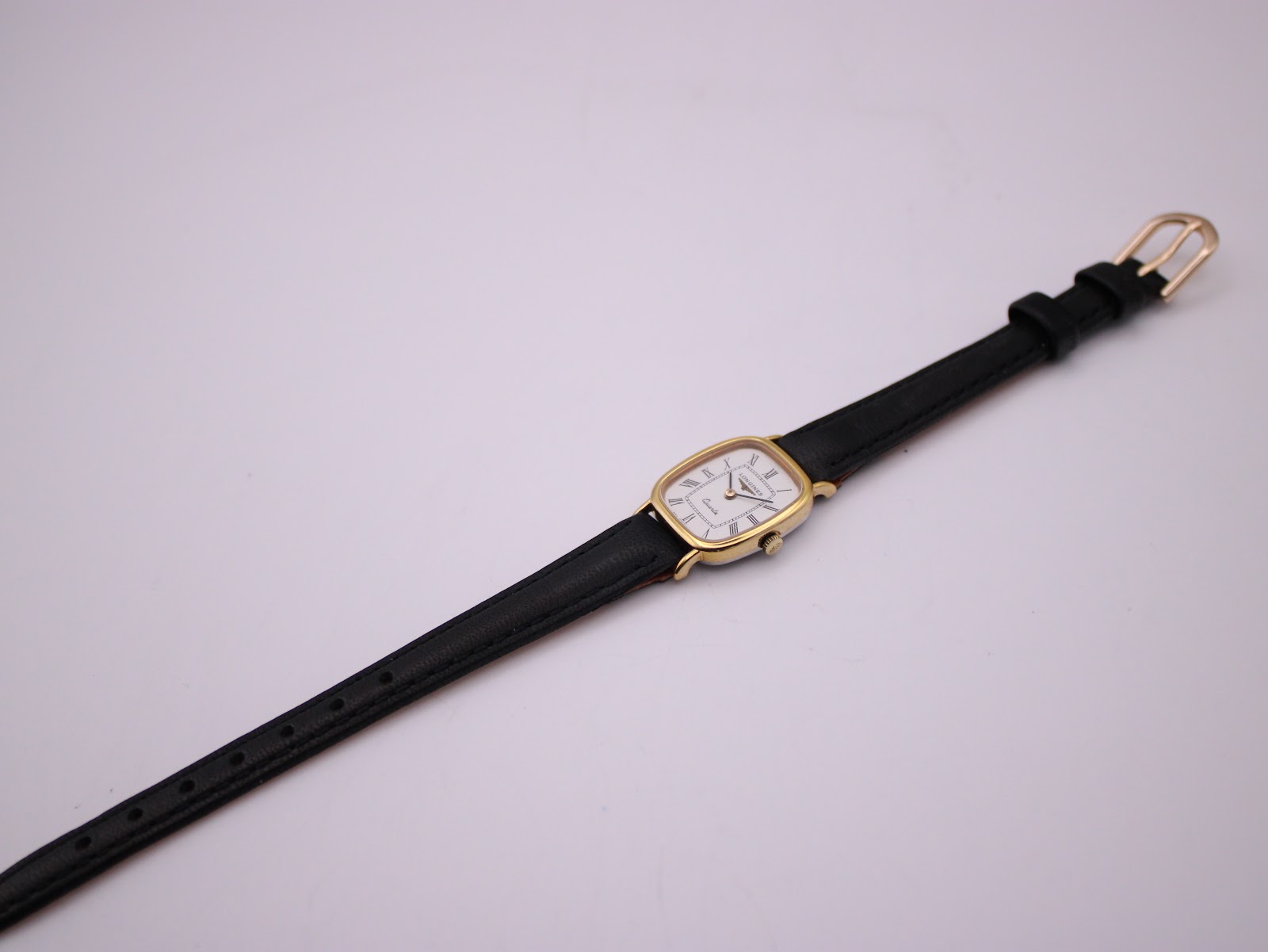 Top-down view of the Longines watch with its black leather strap fully extended on a white background.