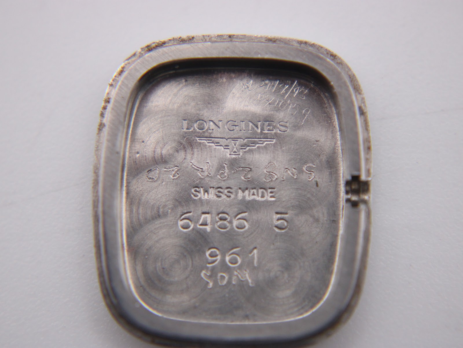 Close-up of the inside of the case back showing Longines branding, 'Swiss Made', model number 6486 5, and service marks including a date '4/12/92'.