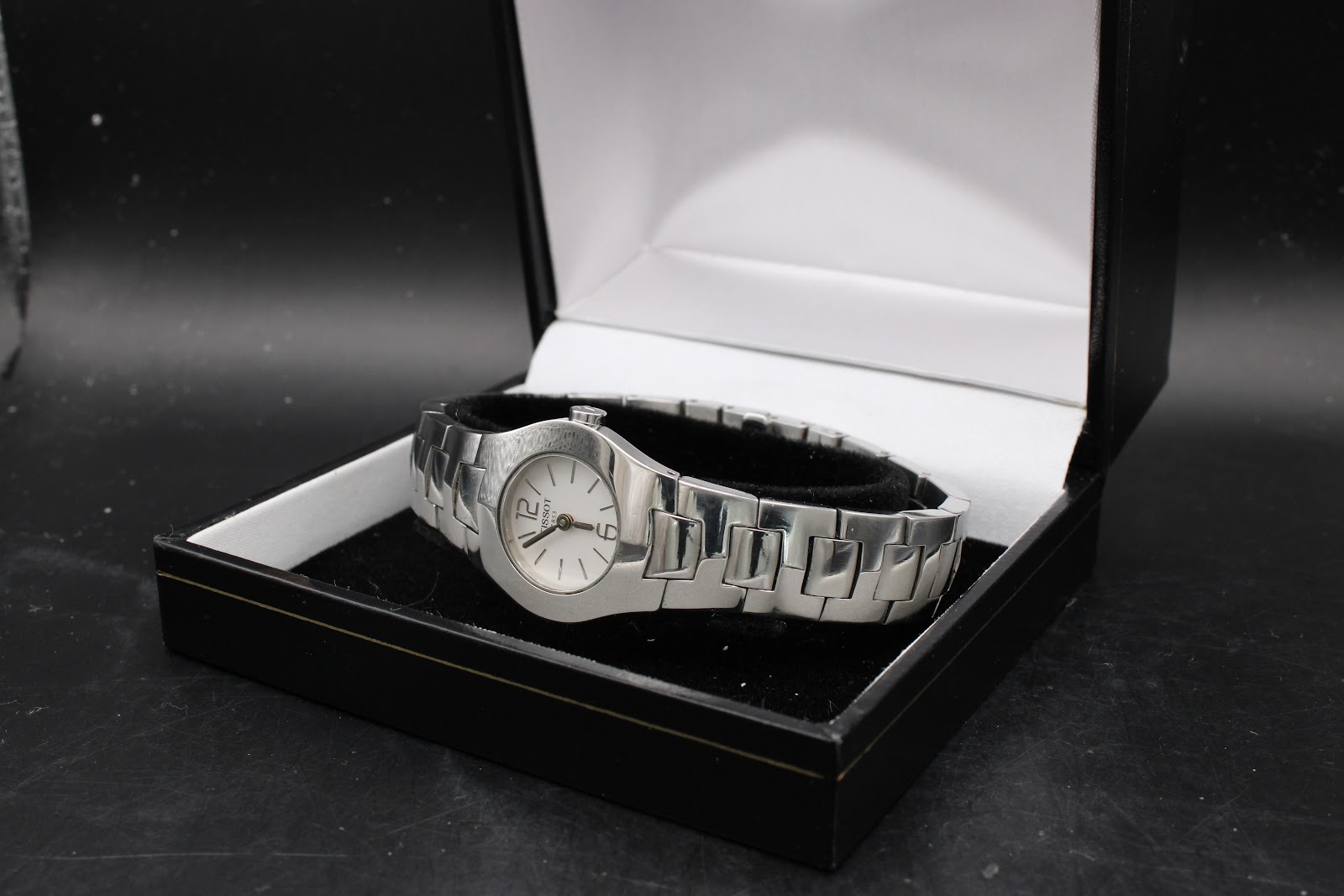 Tissot L520 watch displayed in a simple black presentation box, angled to show the dial and bracelet.