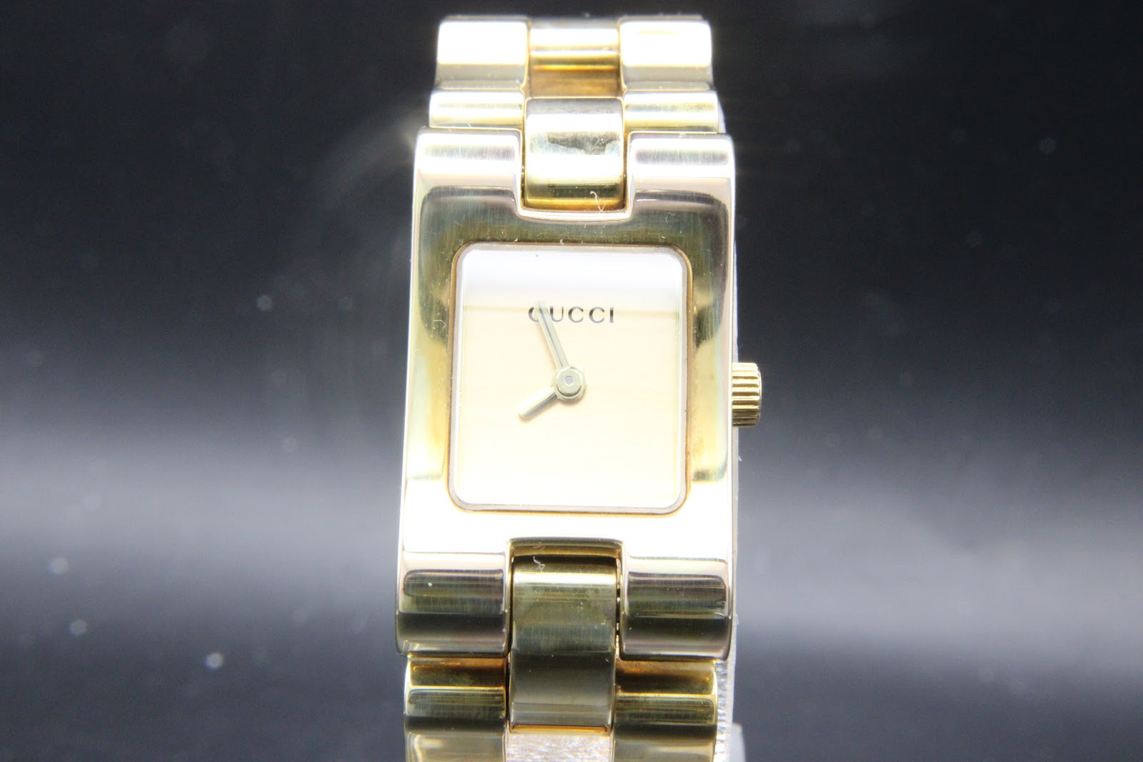 Front view of Gucci 2305L gold-tone watch with rectangular champagne dial, GUCCI branding at 12 o'clock, and integrated bracelet.