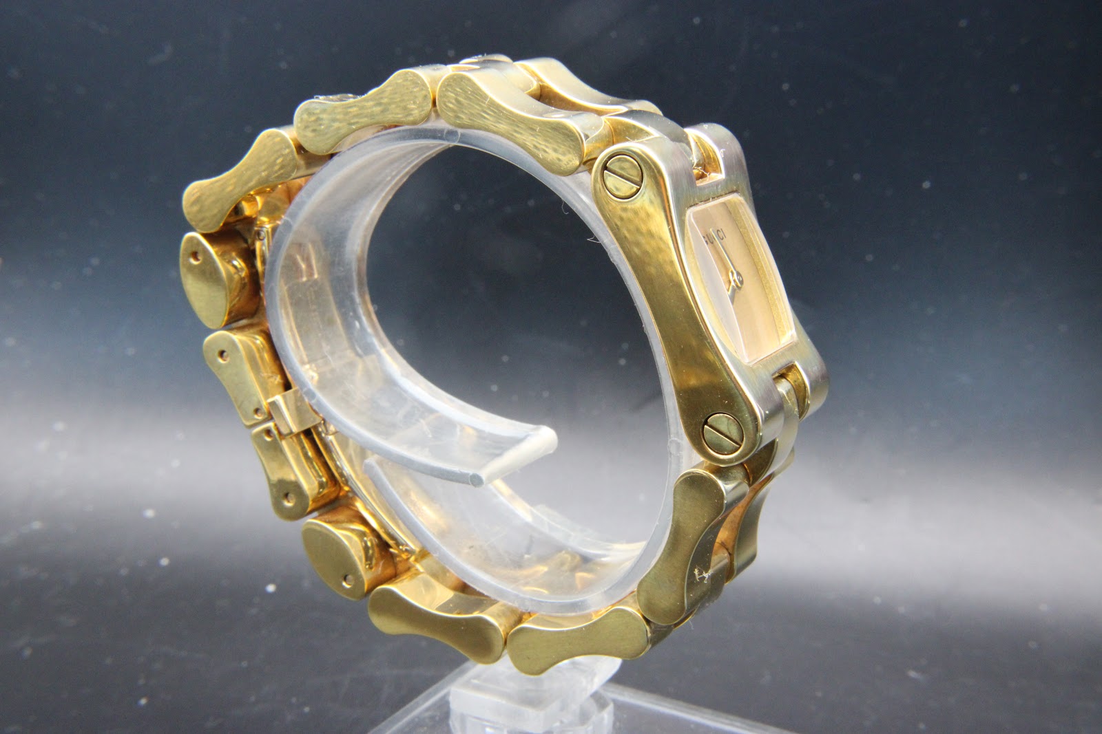 Back-right three-quarter view of the Gucci 2305L integrated bracelet, highlighting the brushed and polished finishing and plating wear on link edges.