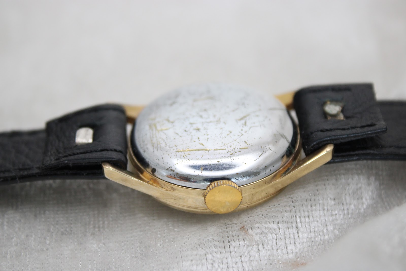 Close-up of the watch's polished stainless steel case back, showing numerous scratches and signs of wear.