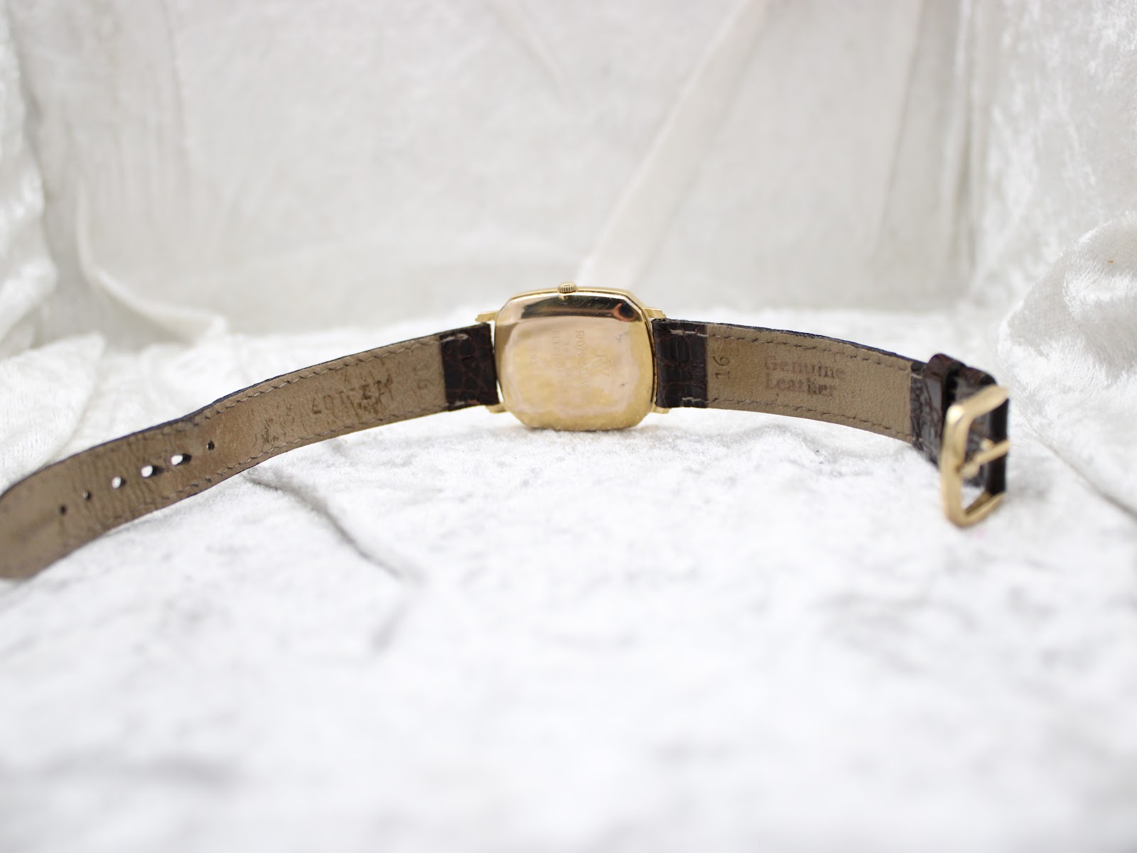 View of the watch with the brown crocodile-pattern leather strap laid open, showing the inside and 'Genuine Leather' stamp.