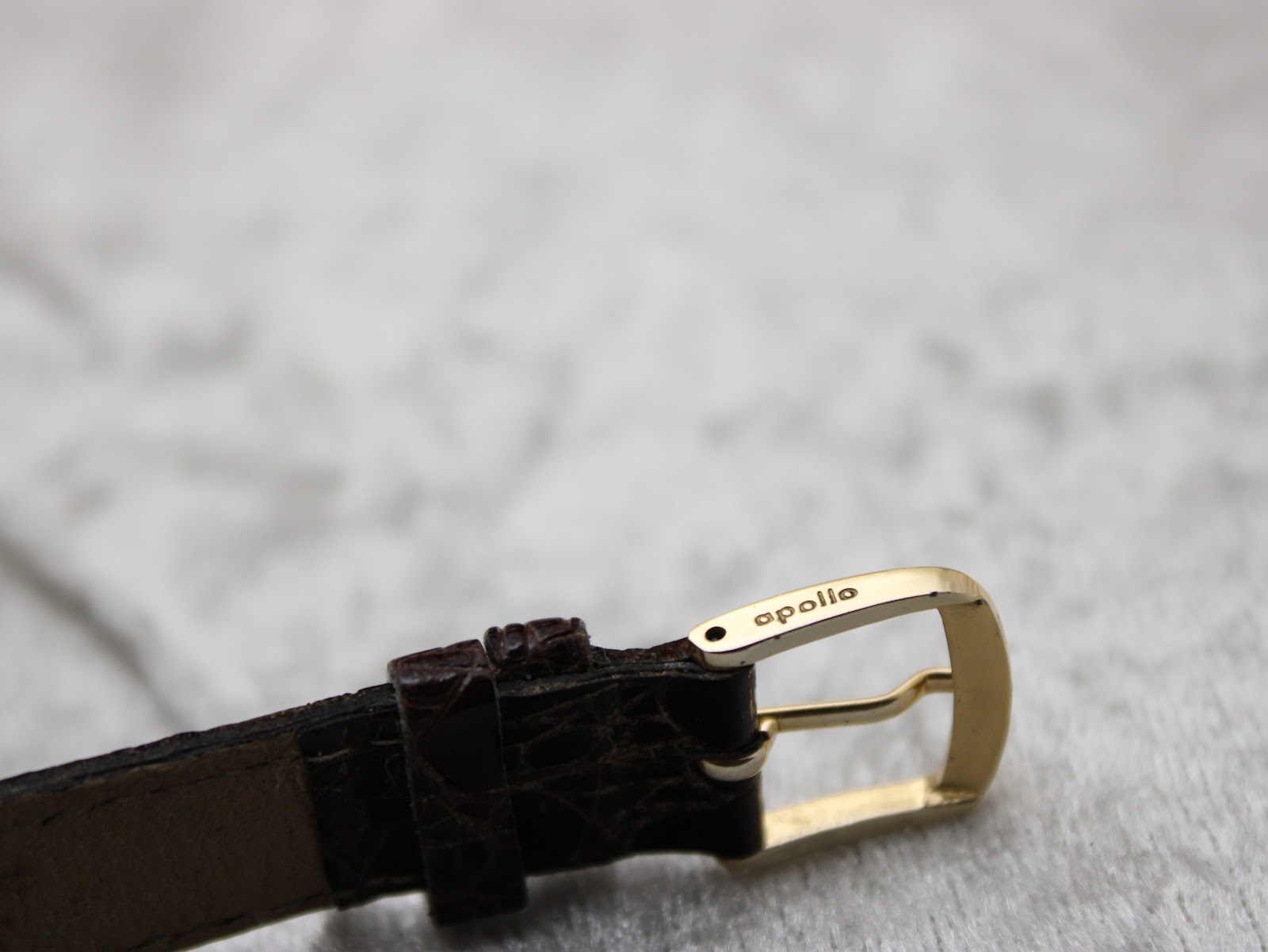 Close-up of the gold-tone buckle, distinctly signed with the 'apollo' brand name.