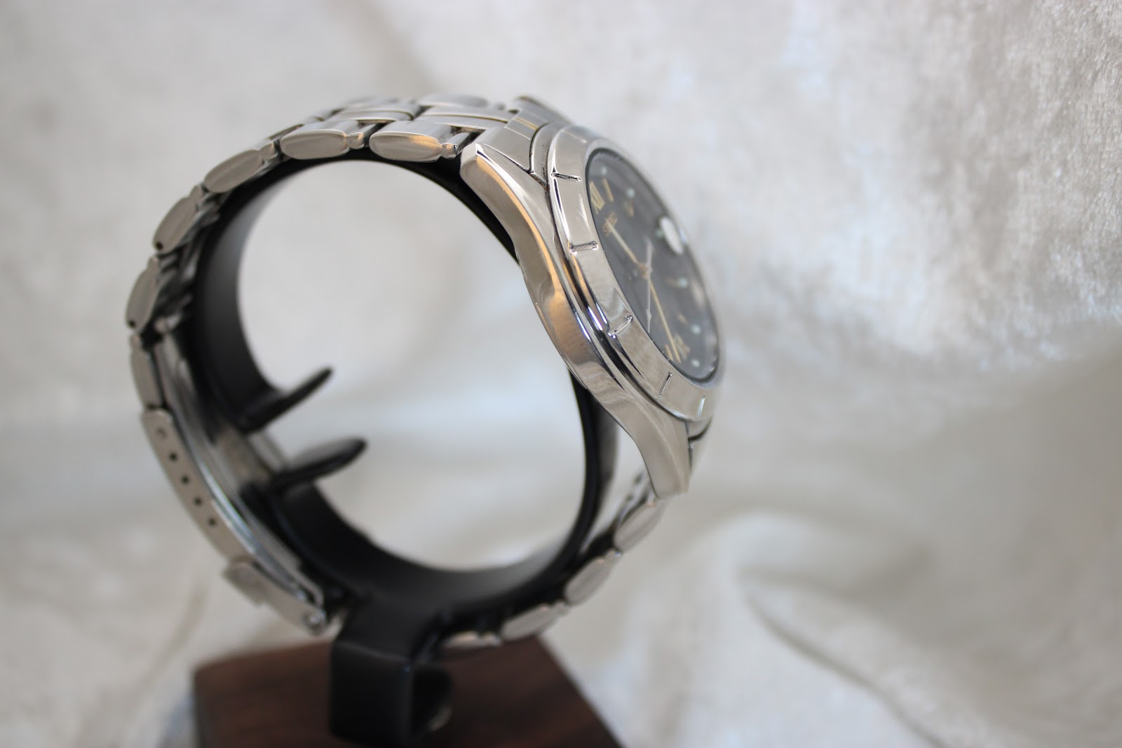 Opposite side view of the Seiko watch on a display stand, showing the case profile and bracelet links.