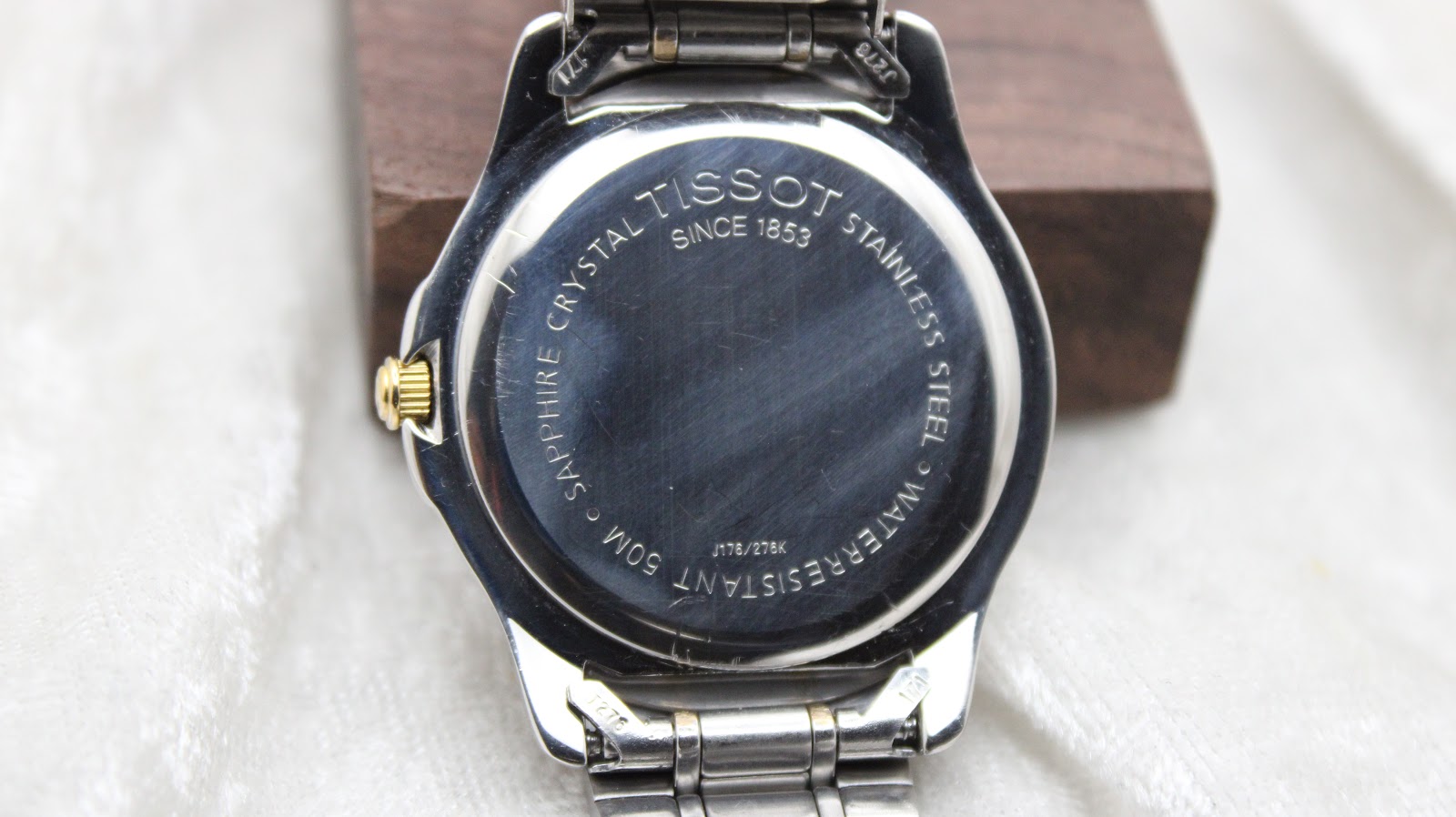 Close-up of the Tissot PR 50 stainless steel case back, showing 'Sapphire Crystal', 'Waterresistant 50M', and model reference J176/278K, alongside minor surface wear.