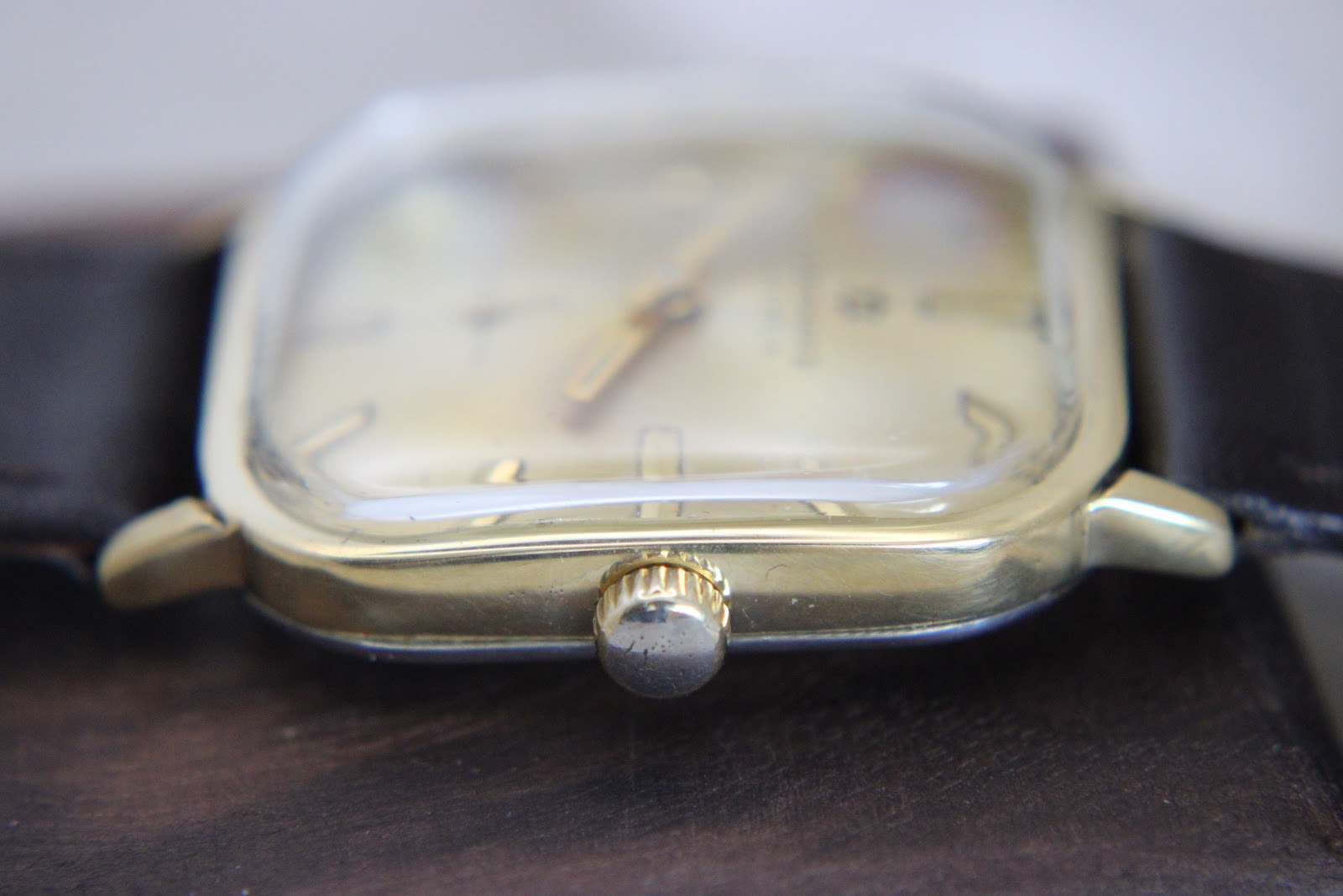 Top-down view of the watch showing the gold-tone crown and the square case shape.