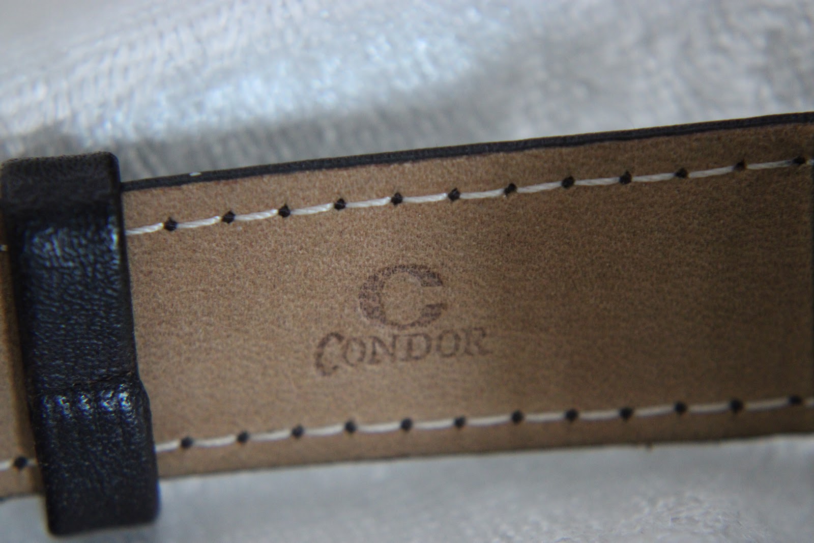 Close-up of the black leather strap's underside, showing the embossed 'Condor' brand logo.