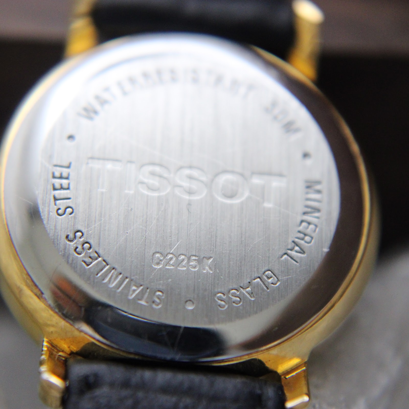 Close-up of the watch case back, showing 'TISSOT', 'C225K', 'STAINLESS STEEL', 'MINERAL GLASS', and 'WATERRESISTANT 30M' engravings.
