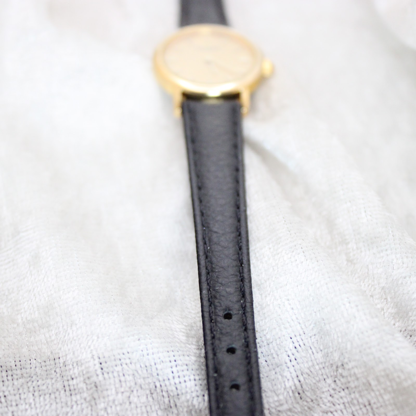 Close-up focus on the black leather strap of the Tissot watch, showing its texture and stitching.