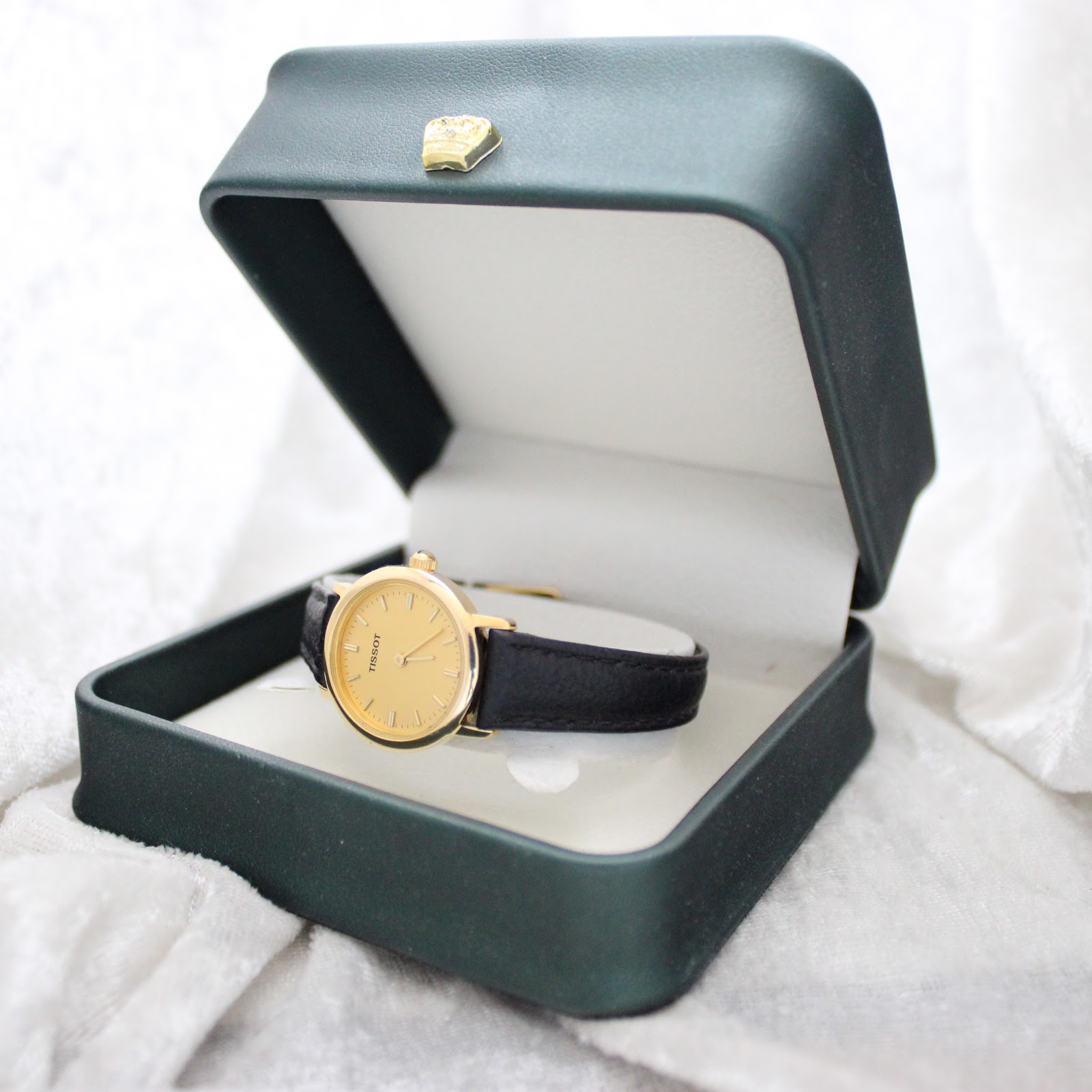 The Tissot C225K watch displayed inside an open, dark green presentation box with a golden crown emblem on the lid.
