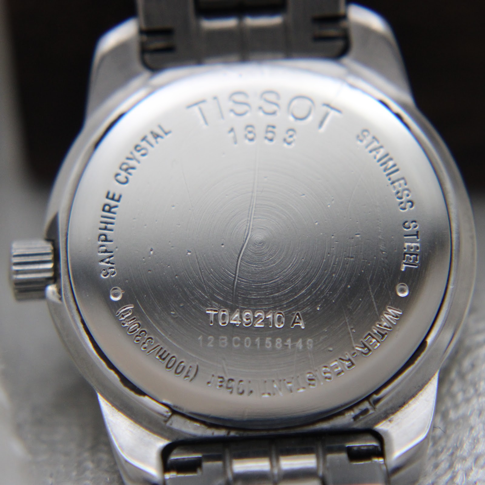 Detailed view of Tissot PR 100 silver dial, Roman numerals, and minute track.