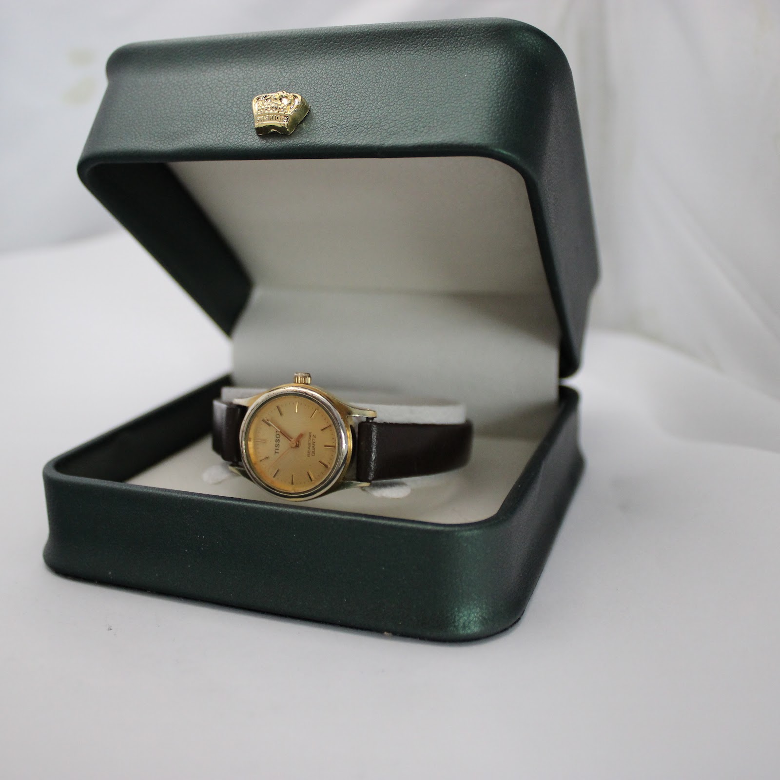 The Tissot Seastar watch displayed within an open, dark green watch presentation box with a gold crown emblem.