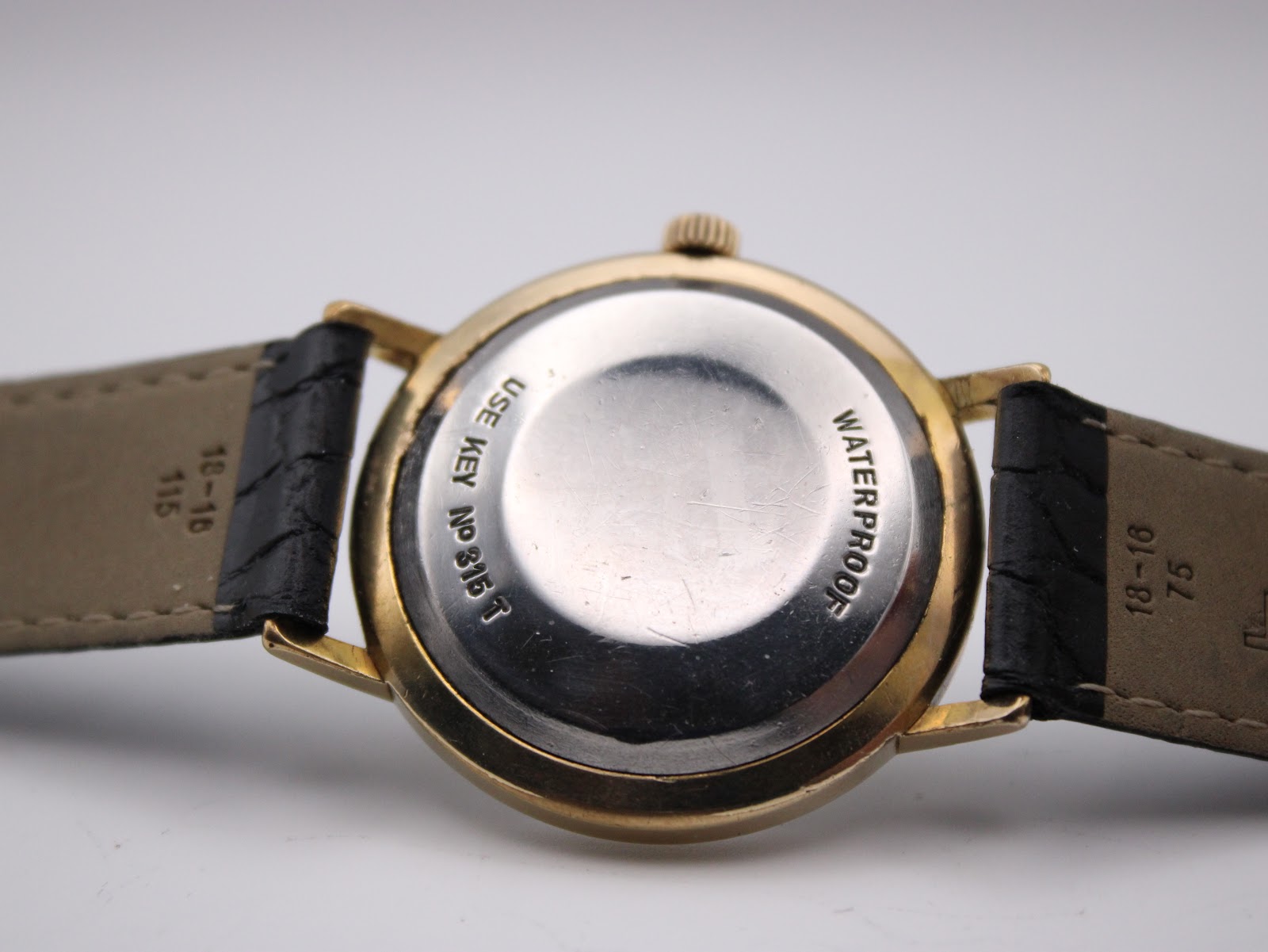 Black leather strap with gold-tone Tissot signed buckle.