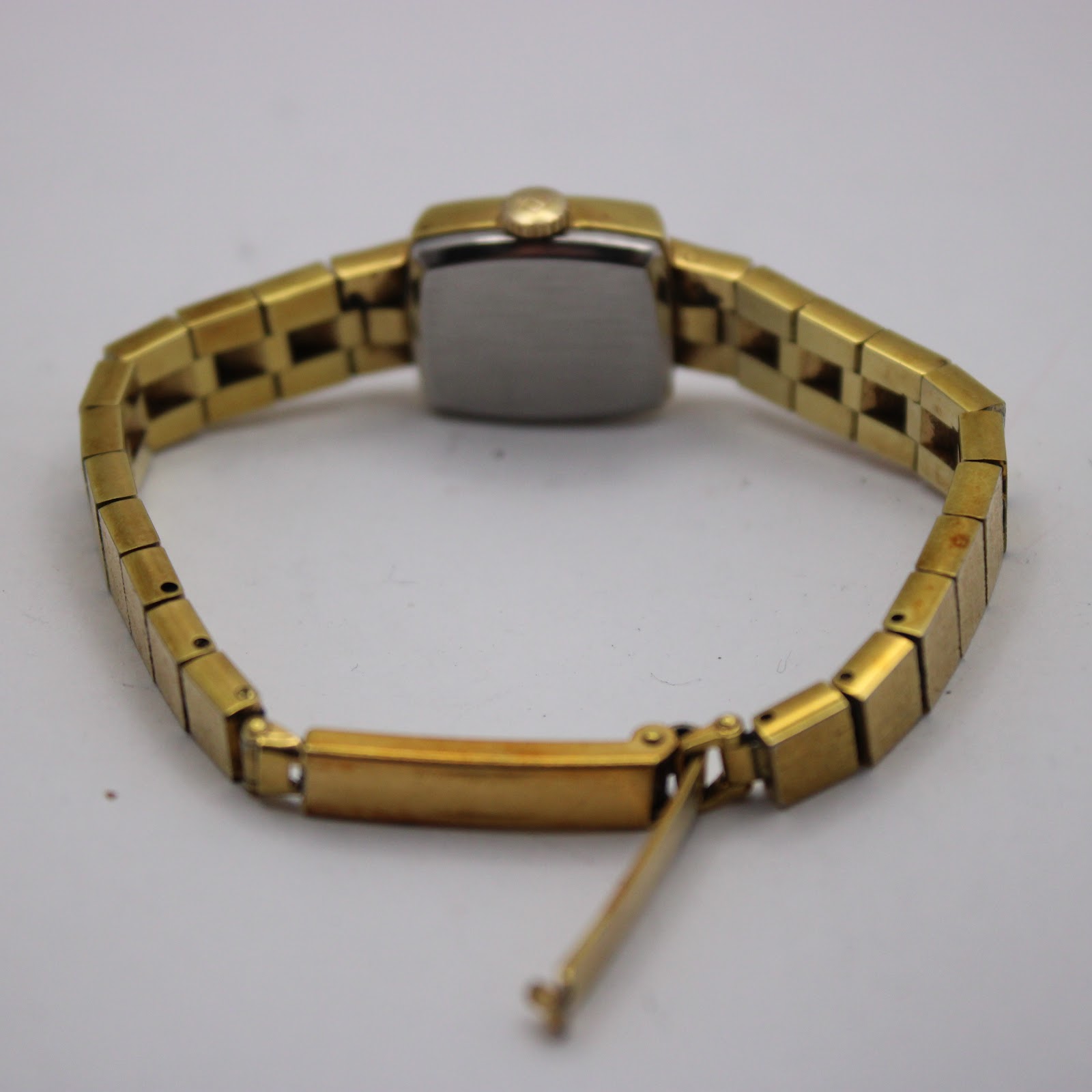 Rear view of the watch showing the stainless steel case back and the integrated bracelet with open clasp.