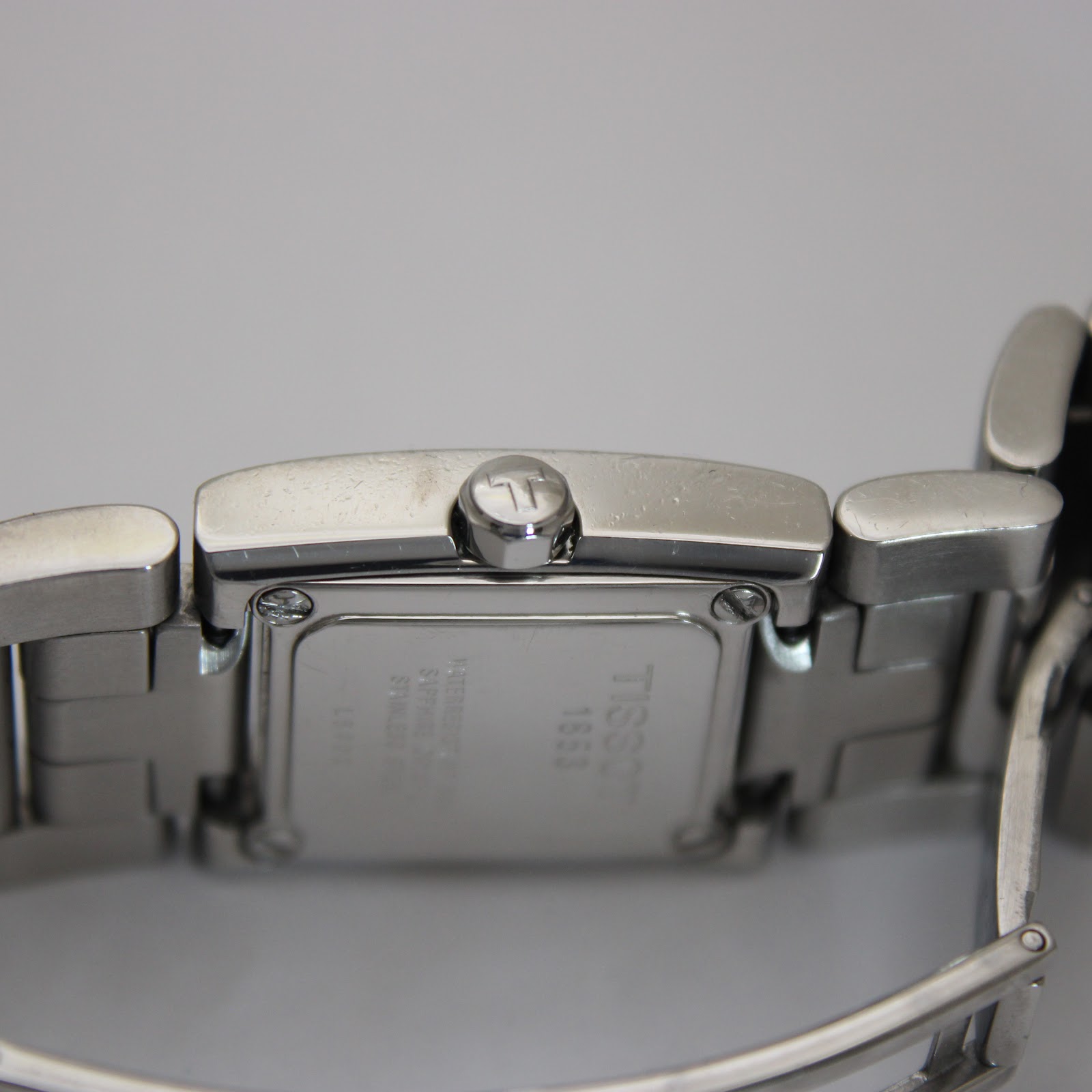 Close-up of the Tissot signed crown and the detailed engravings on the brushed stainless steel case back.