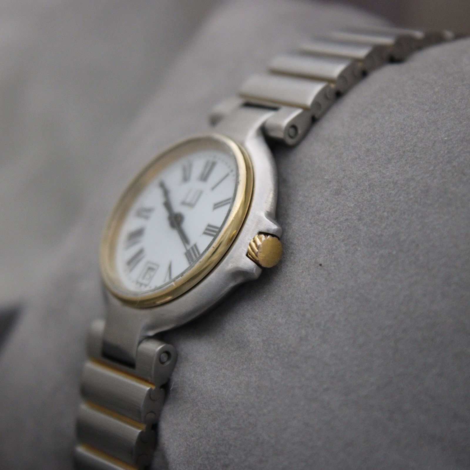 Angled view of Dunhill watch showing the side profile and gold-tone fluted crown.