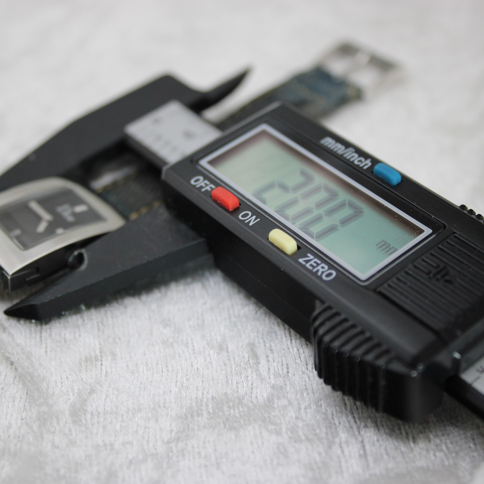 Digital caliper displaying 28.00 mm, measuring the length of the watch case.