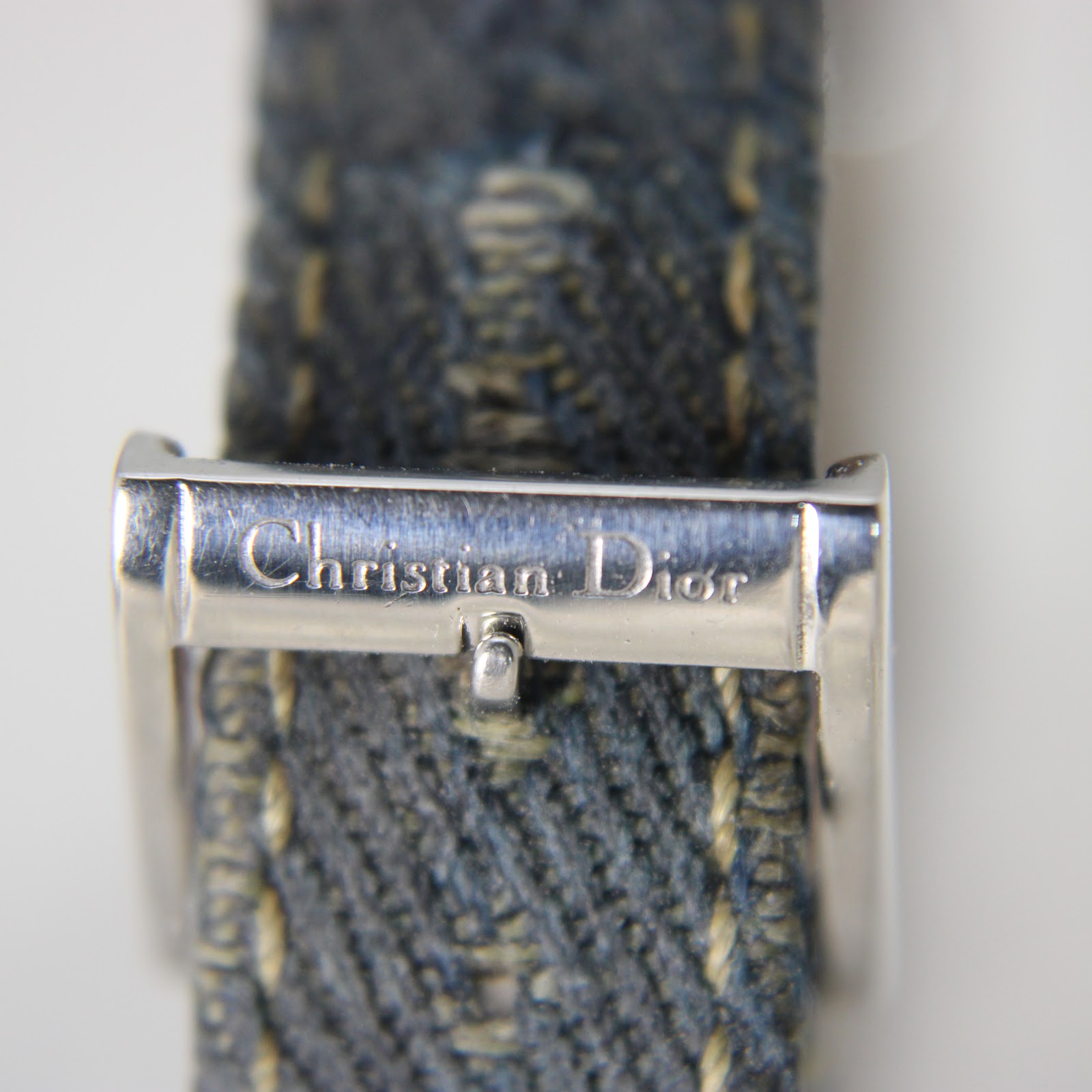 Close-up of the original Christian Dior signed buckle on the denim strap.