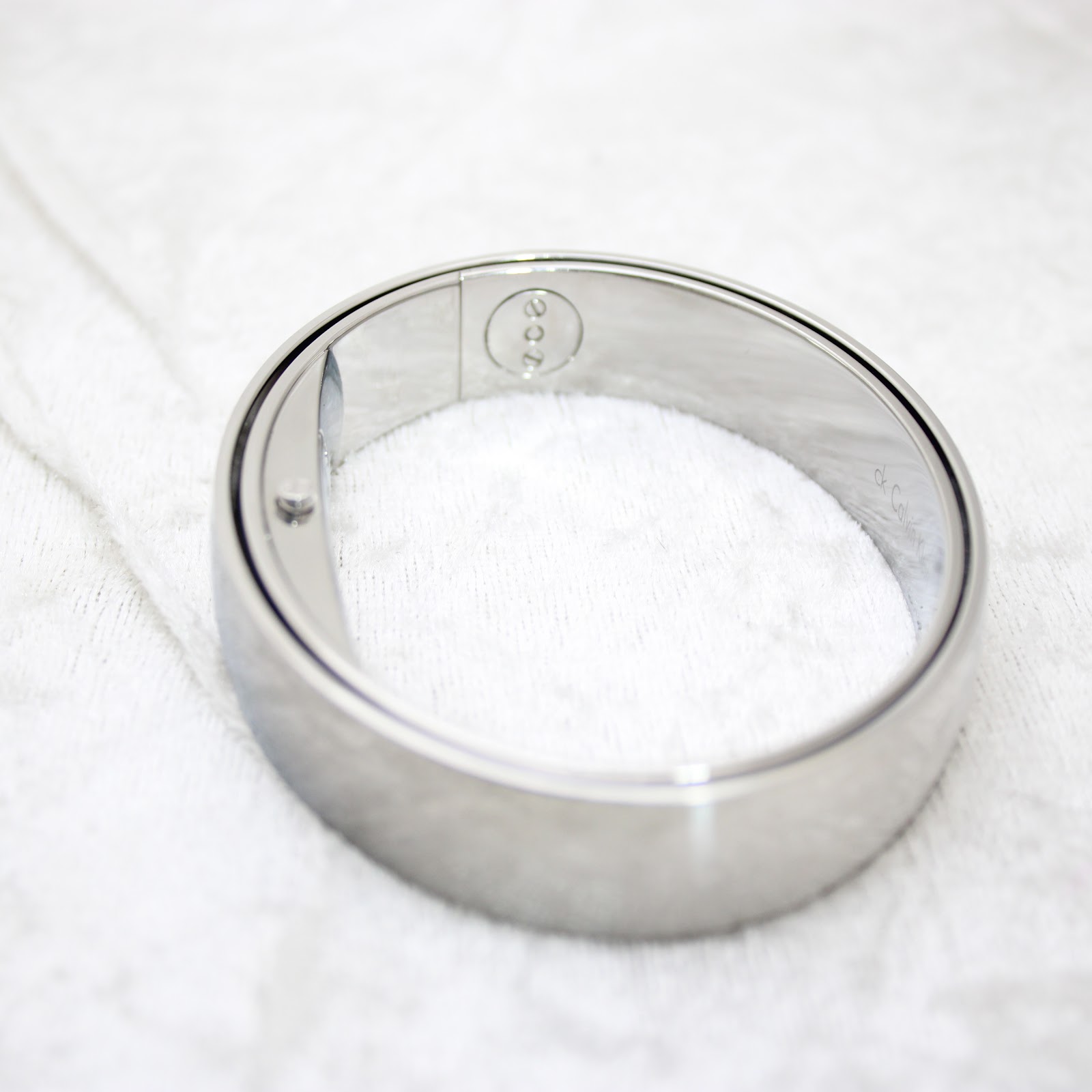 Side view of the polished stainless steel bangle watch, showing the internal clasp mechanism.