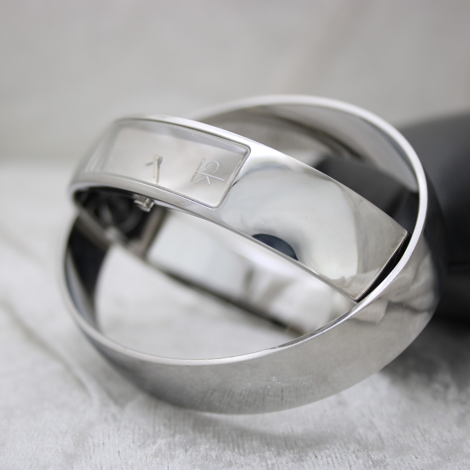 Dynamic angled shot of the minimalist Calvin Klein bangle watch, highlighting its reflective stainless steel finish.