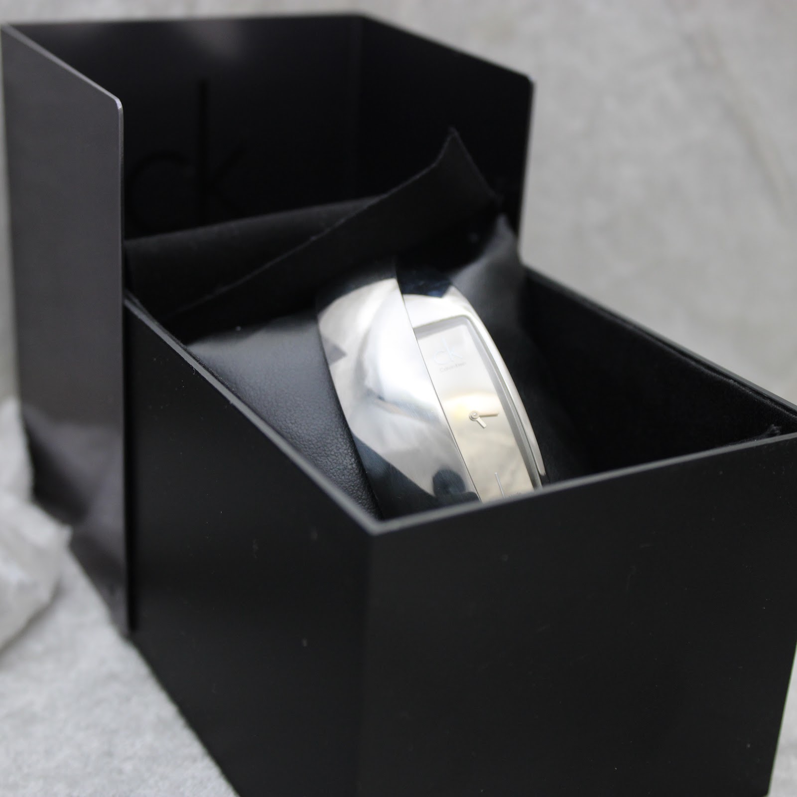 The Calvin Klein bangle watch nestled inside its original black presentation box with a velvet interior.