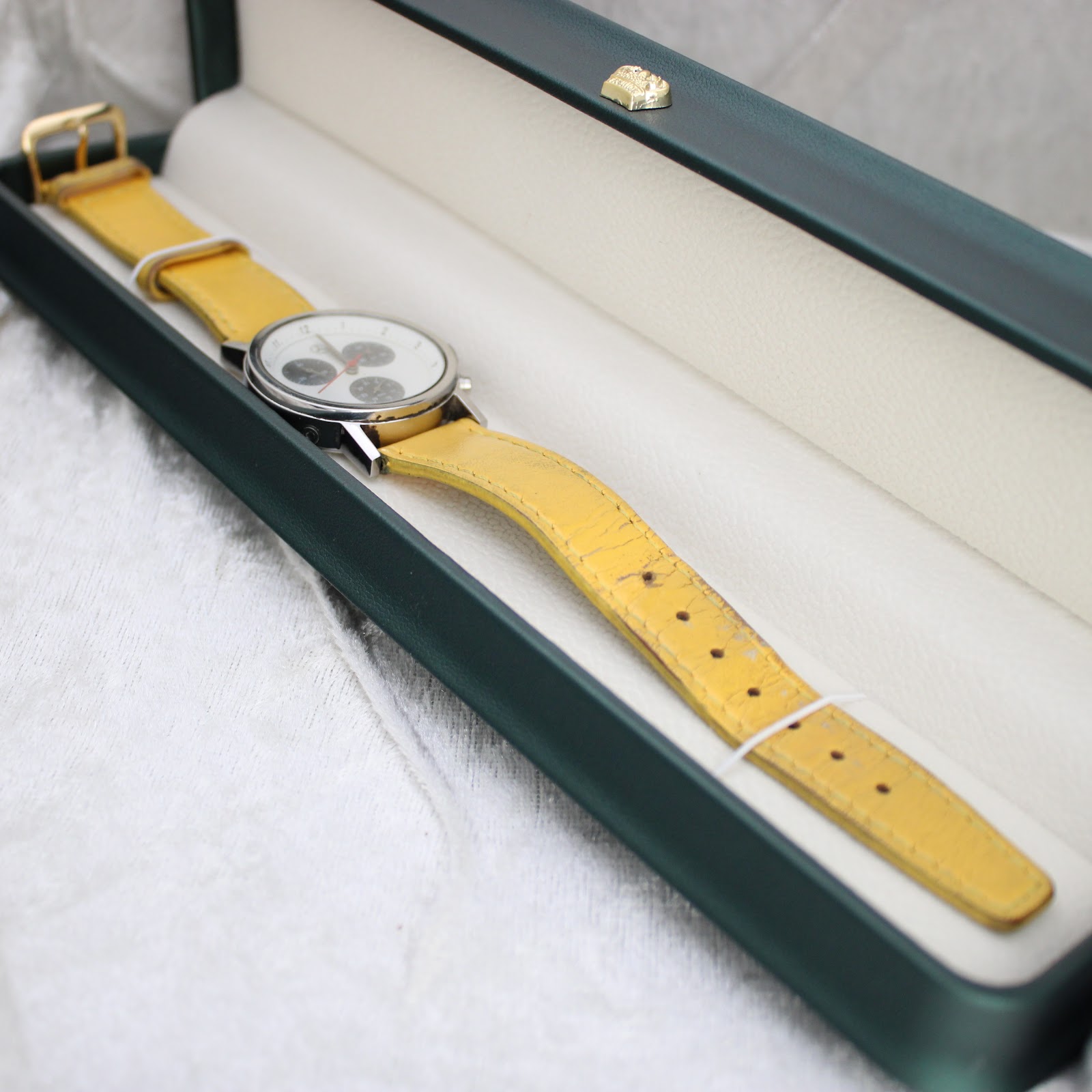 Mercedes-Benz SLK chronograph watch with yellow strap presented in a dark green watch box.