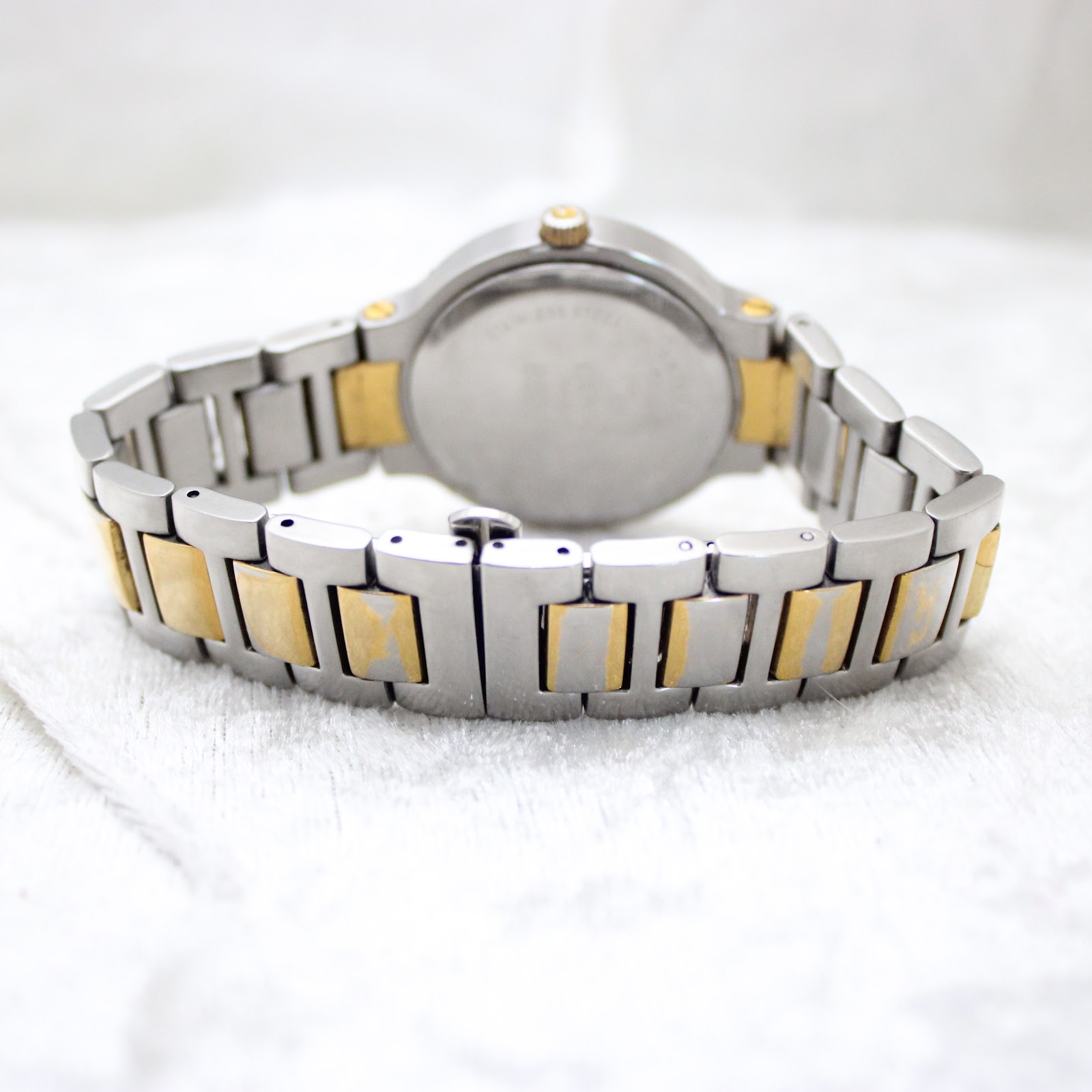 Rear view of the watch and two-tone bracelet, showing the stainless steel case back and signed fold-over clasp.