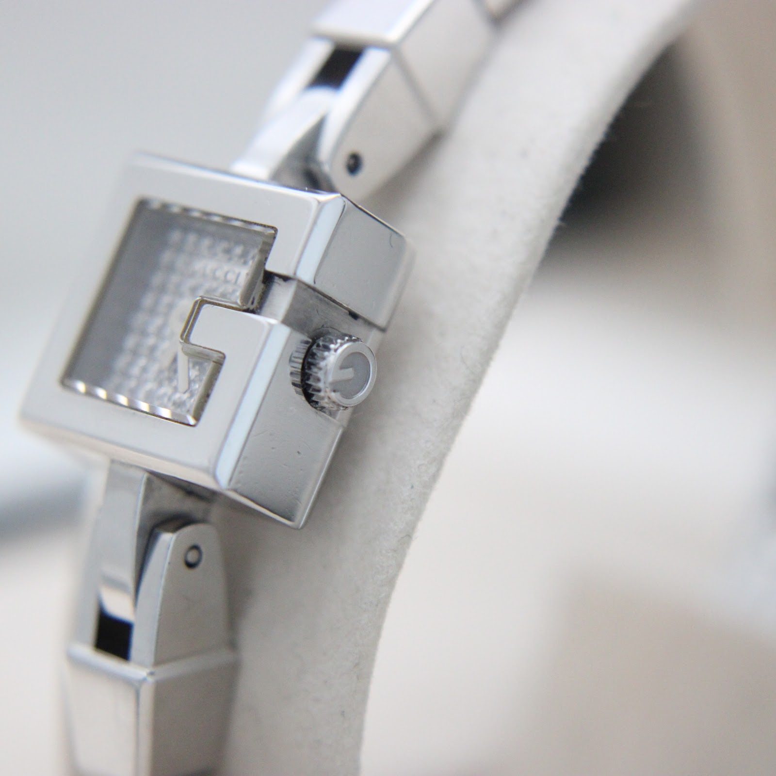 Side view of the Gucci 102 G-frame watch case and crown, showing the 'G' logo on the crown.