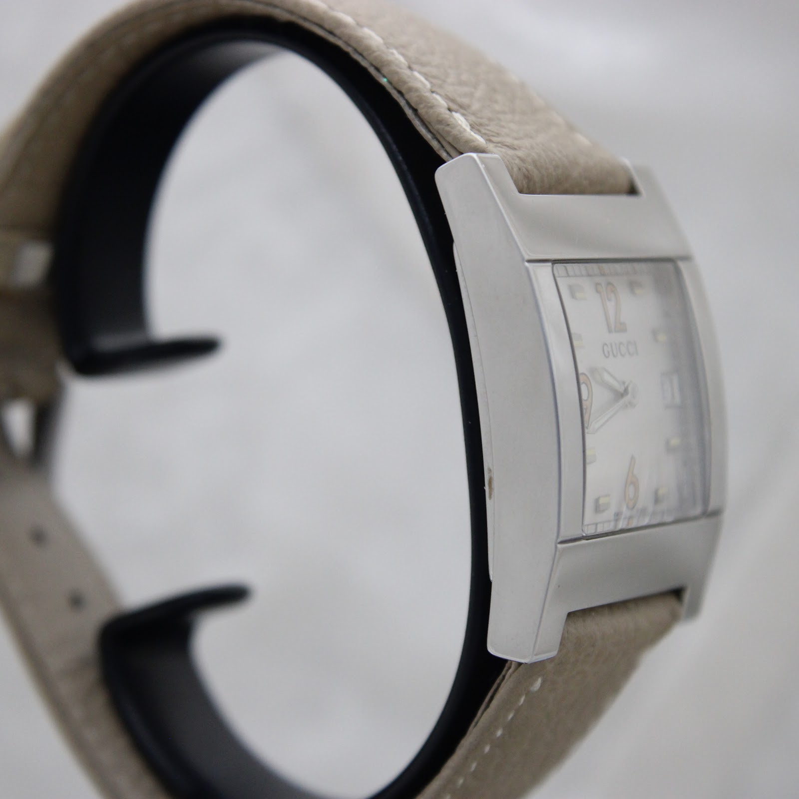 Another side view of the Gucci 7700M, highlighting the case profile and beige strap.