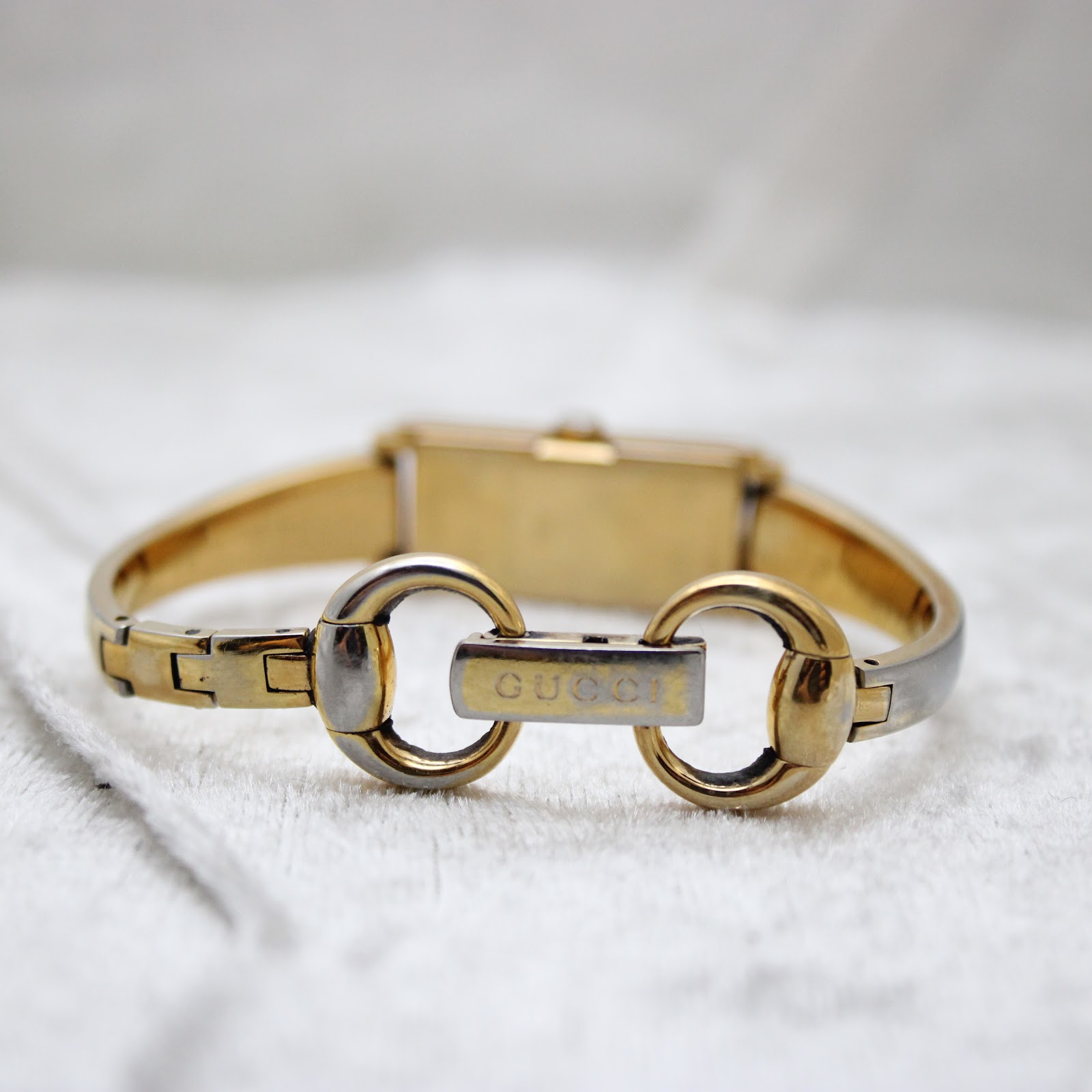 Close-up of the Gucci signed two-tone bracelet clasp, showing the interlocking G logo and "GUCCI" engraving.