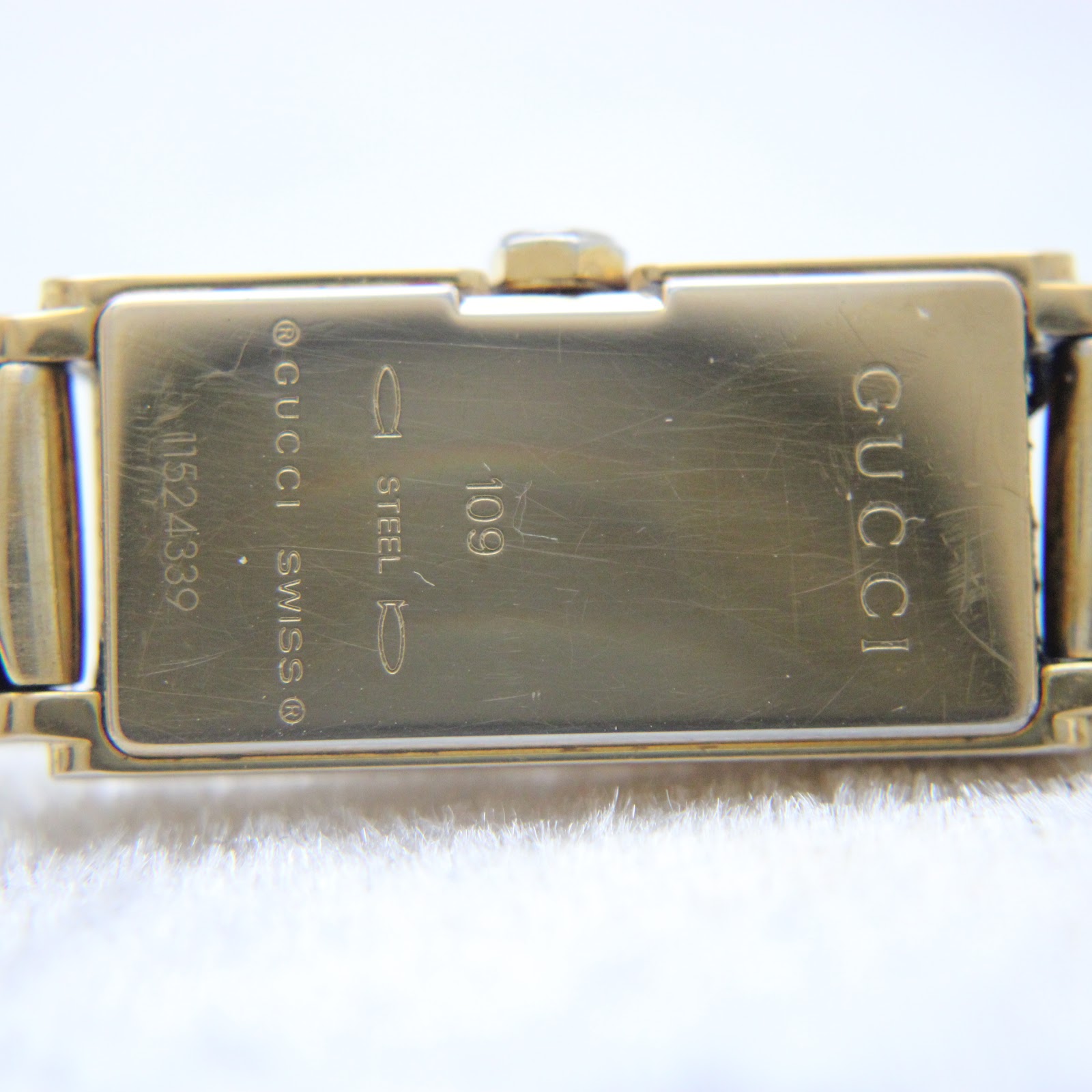 Detailed close-up of the watch's snap-back case, showing "GUCCI", "109", "STEEL", and serial number engraving.