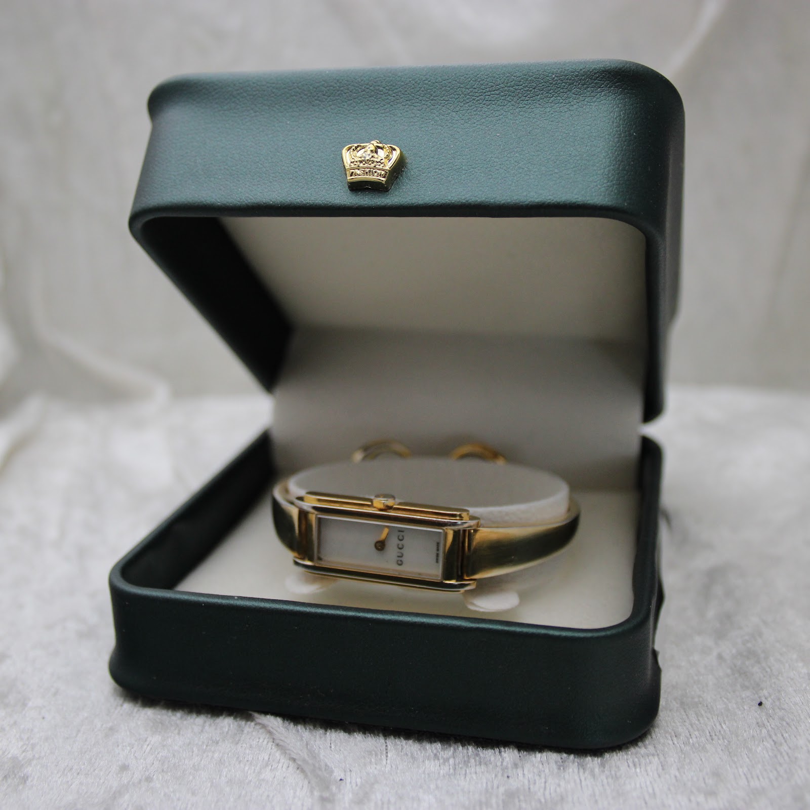 The Gucci 109 watch resting inside a dark green presentation box with a crown emblem.