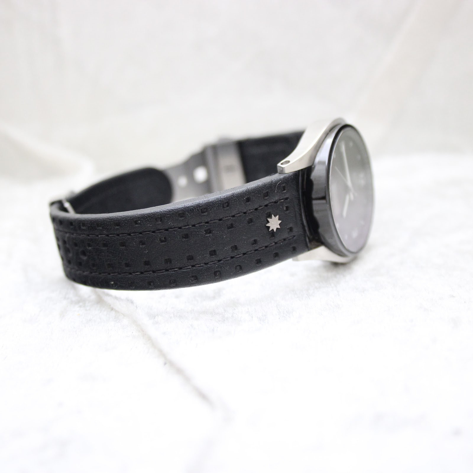 Oblique view of the perforated leather strap, featuring a subtle decorative star emblem.