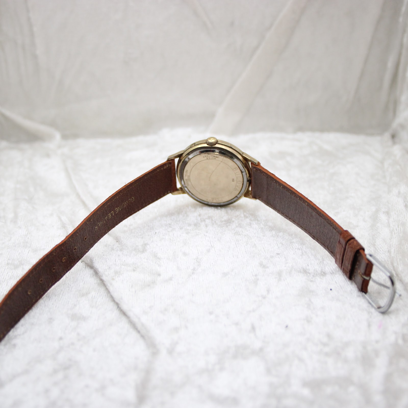View from the back of the watch, showing the brown leather strap laid flat and the case back details.