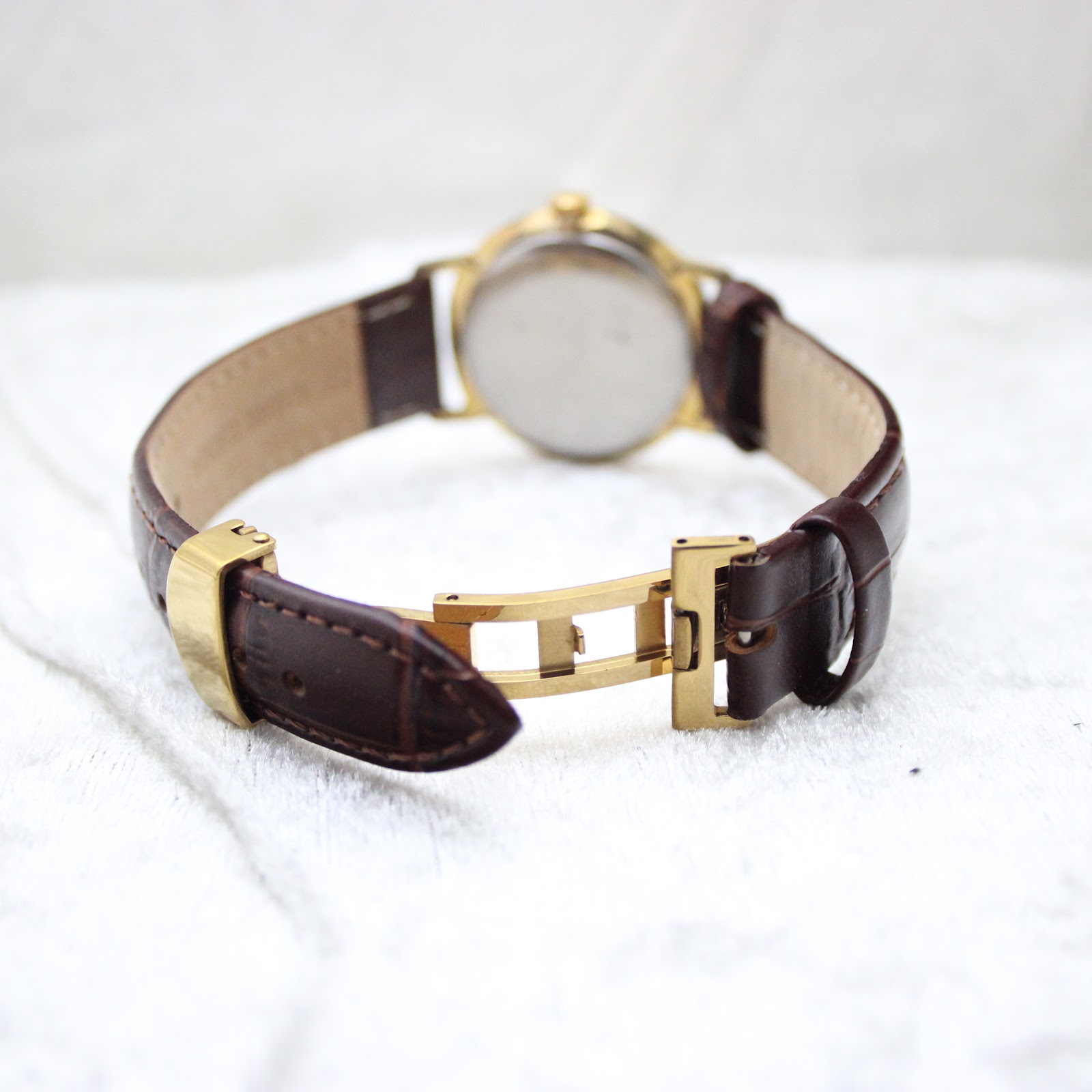 Close-up of the gold-tone butterfly deployant clasp on the brown leather strap.