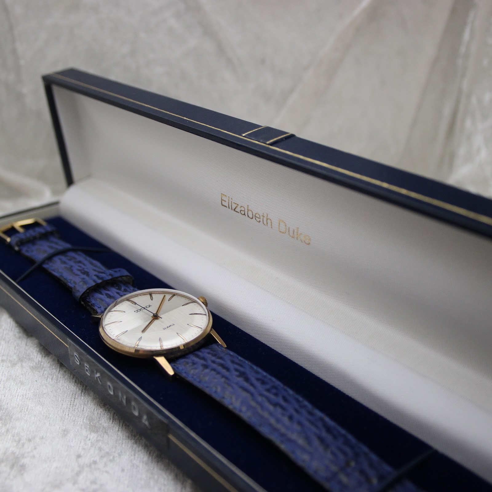 Sekonda watch on its blue strap presented in a dark blue watch box, ready for dispatch.