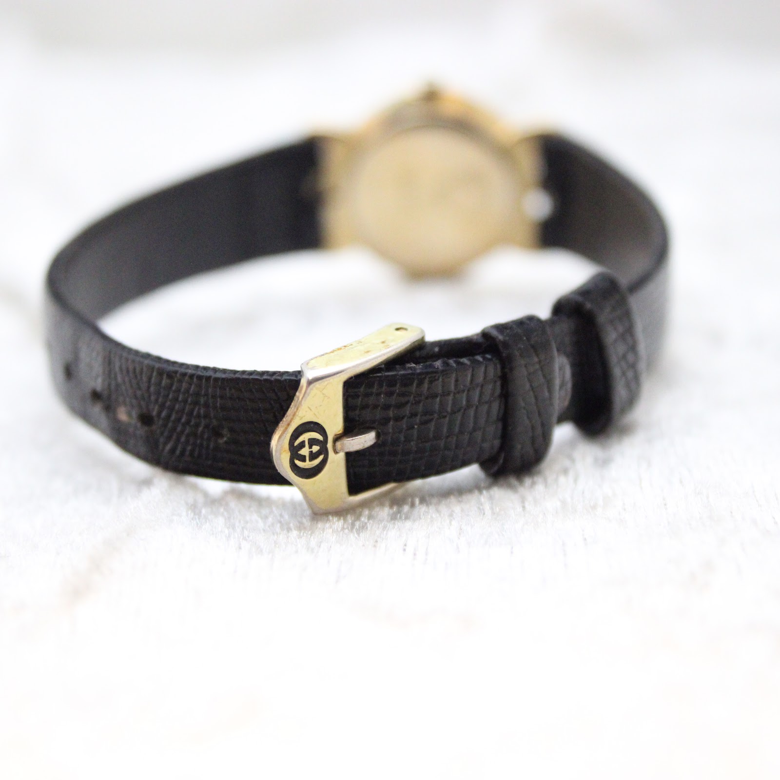 Close-up of the original black textured leather strap and the Gucci-signed buckle.