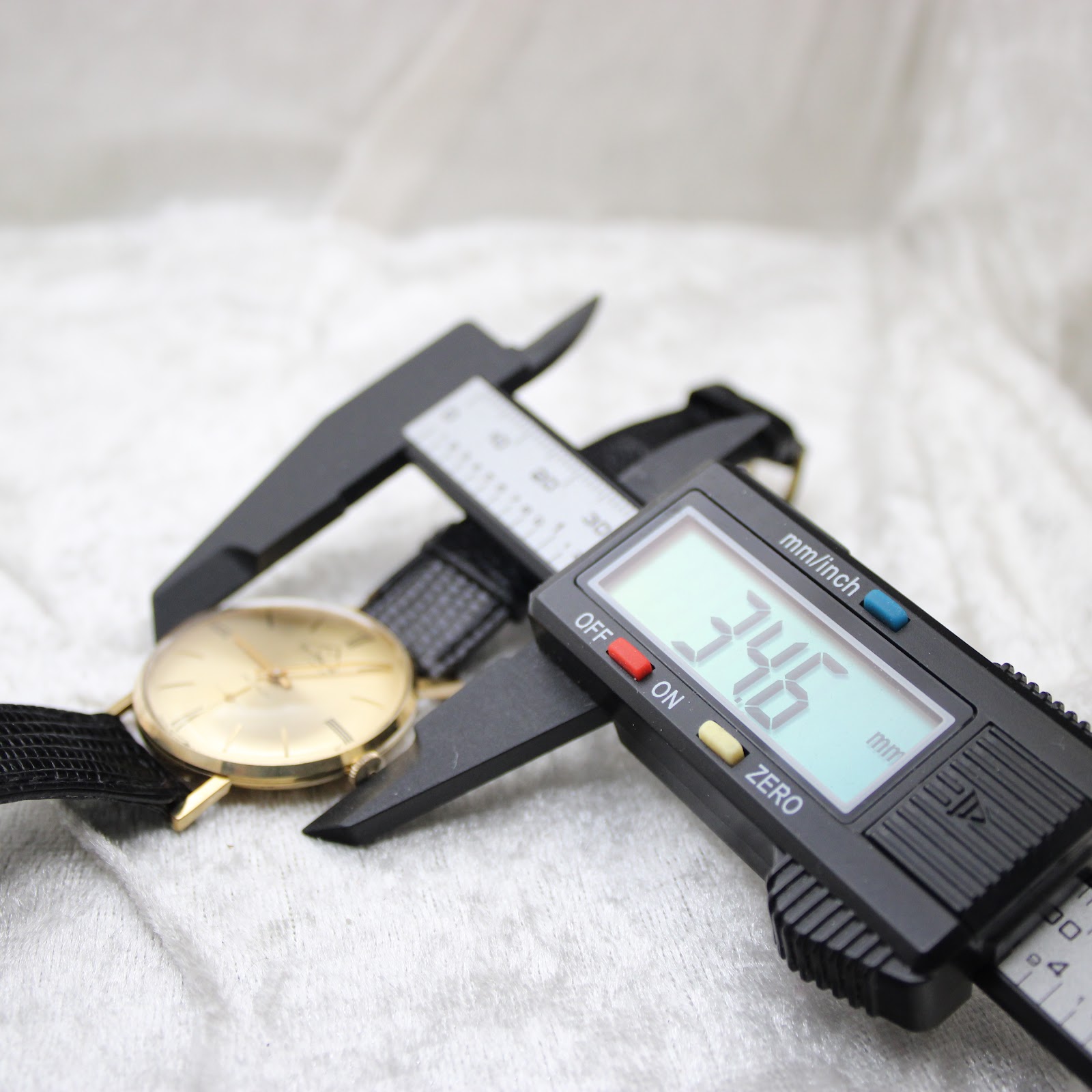 Digital caliper measuring the case diameter of the Mondaine watch, showing a reading of 34.6mm.