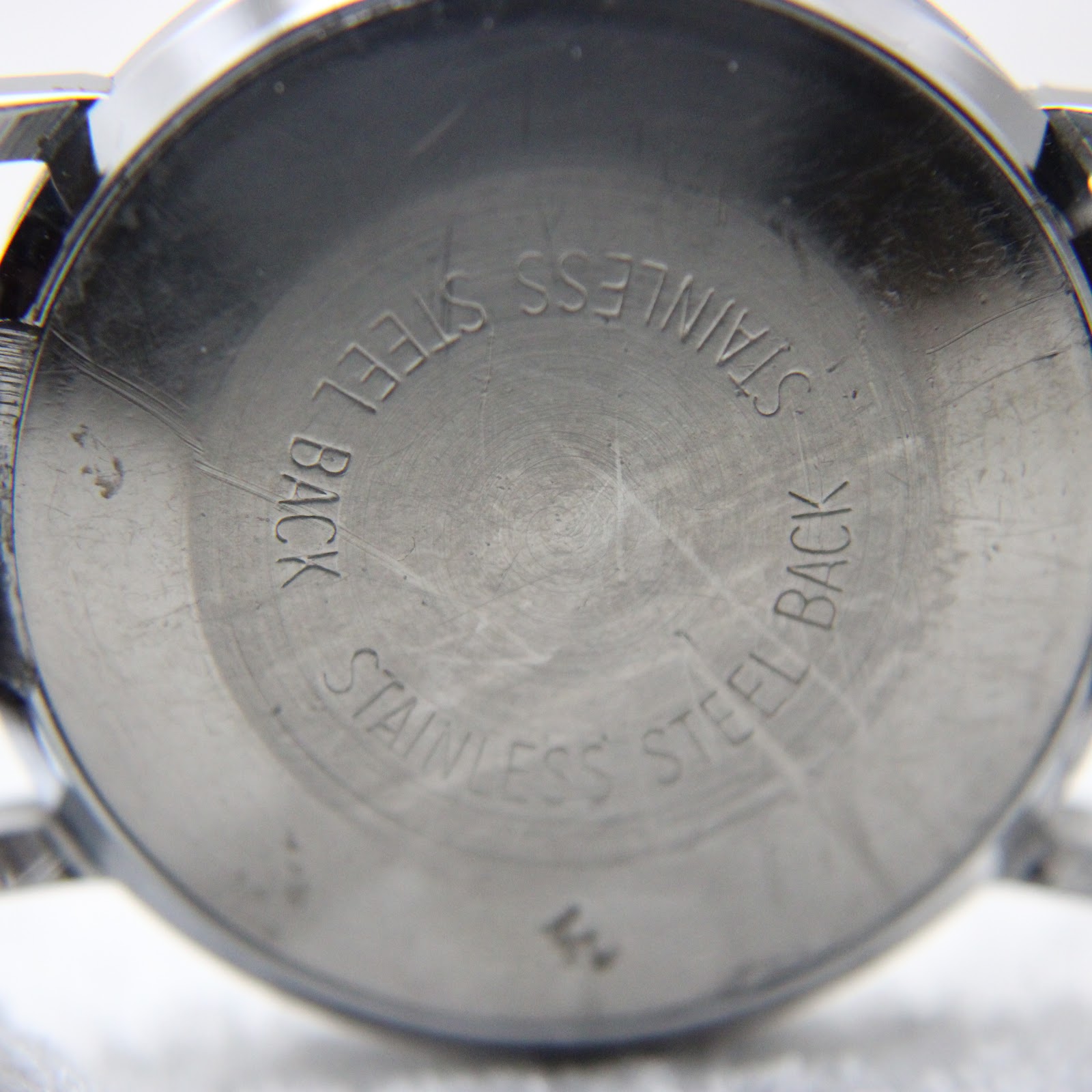 Close-up of the watch's stainless steel case back with 'STAINLESS STEEL BACK' engraved in a circular pattern.