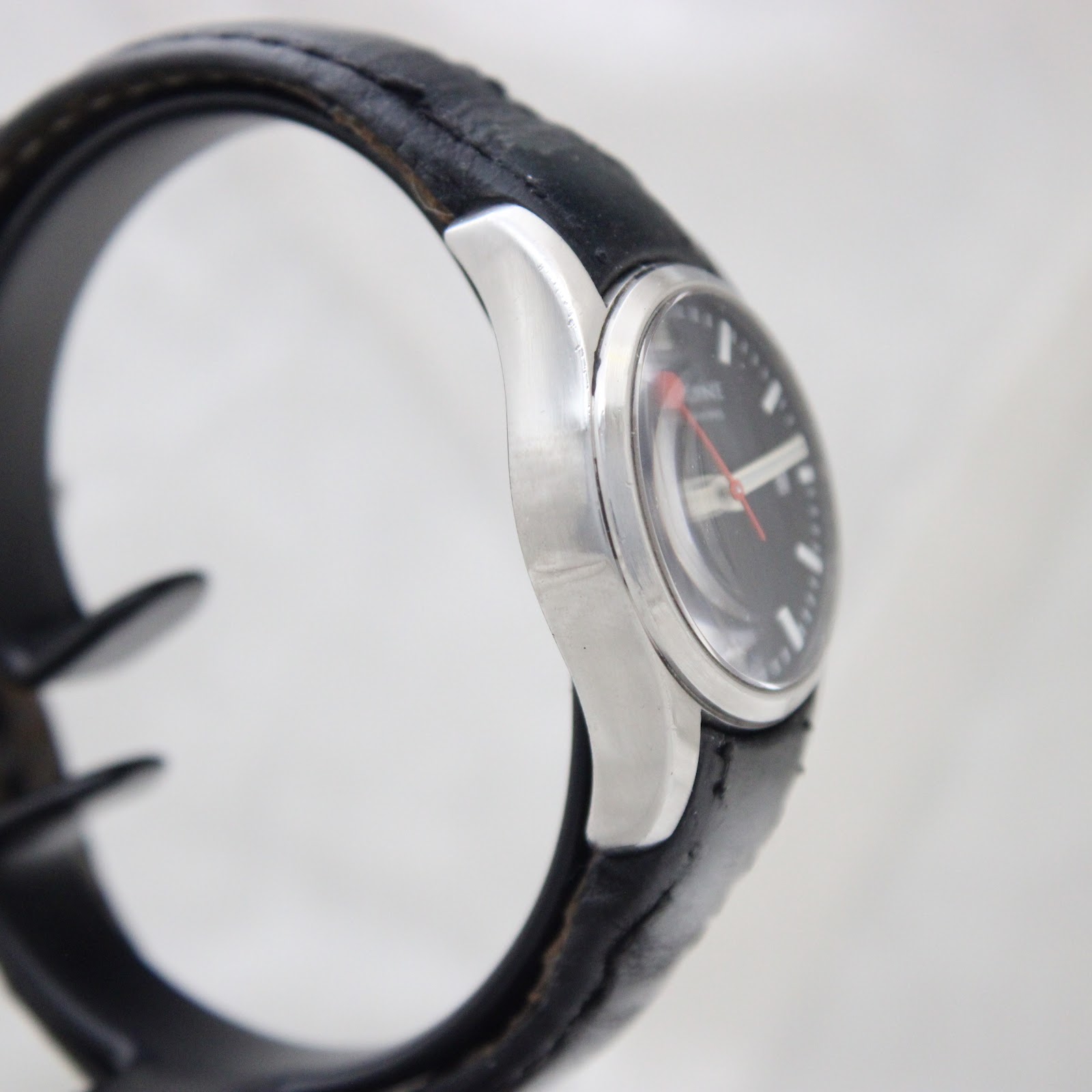 Other side view of the Mondaine watch showing the brushed stainless steel case and black leather strap