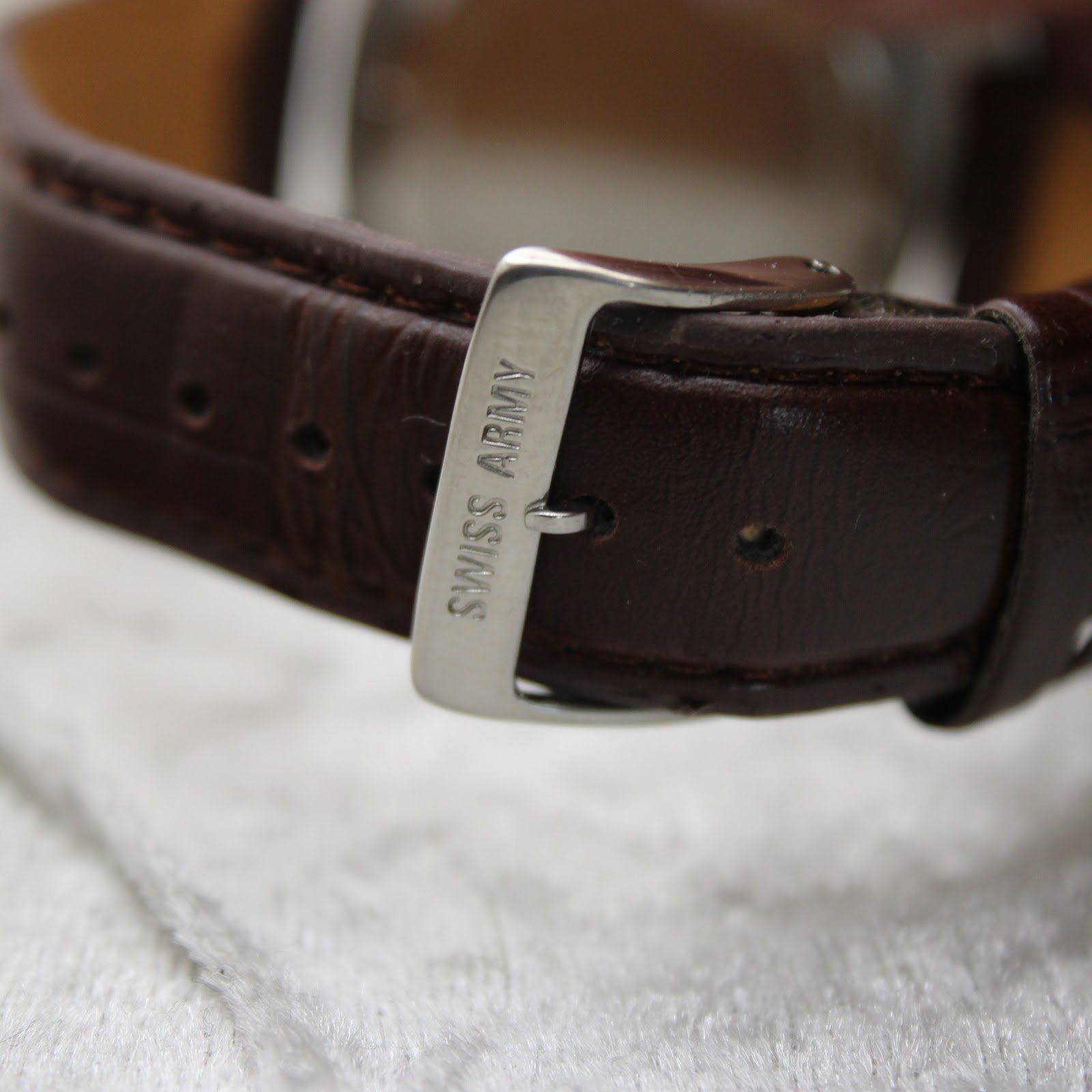 Close-up of the stainless steel buckle signed "SWISS ARMY" on the brown leather strap.