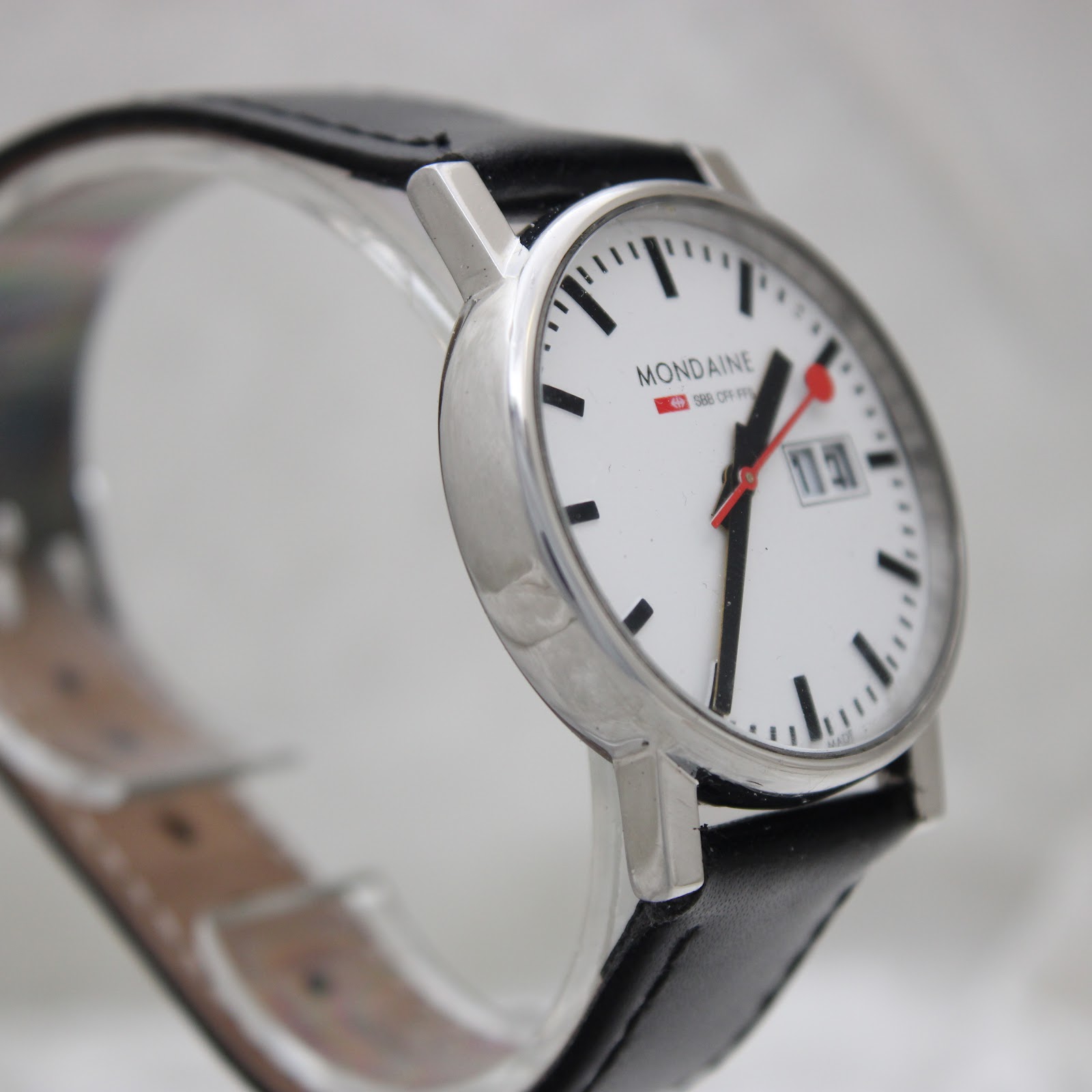 Another angled view from the opposite side, showcasing the minimalist aesthetic and how the black leather strap connects to the lugs.