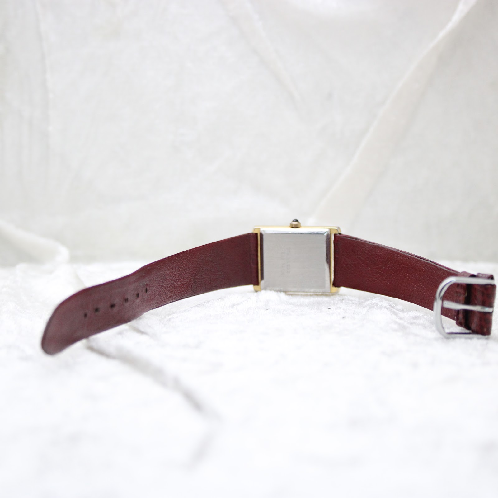 View of the Corteal watch from the rear, showing the stainless steel case back and the full length of the burgundy leather strap.