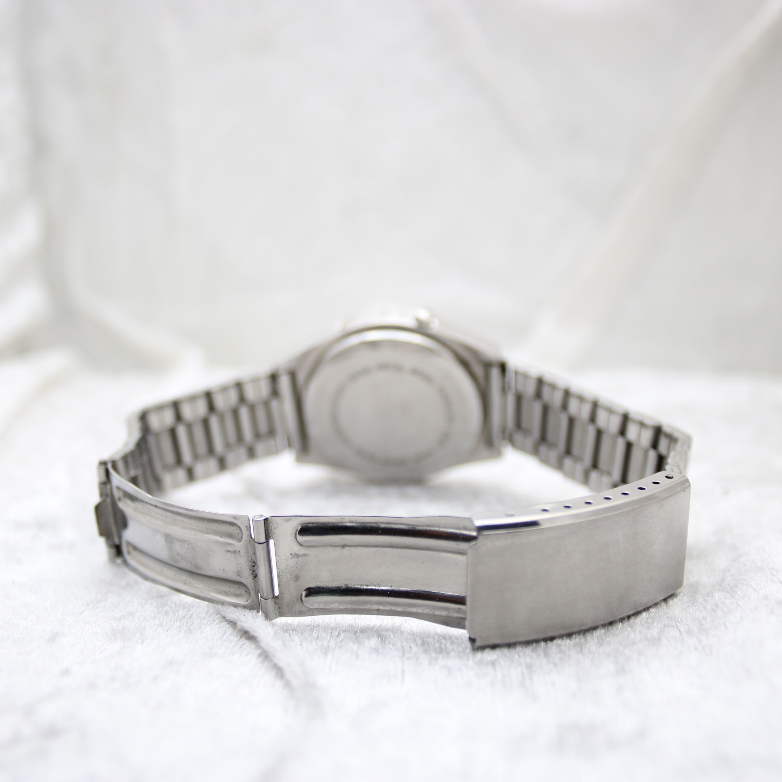 Rear view of the integrated stainless steel bracelet and unsigned fold-over clasp, with the watch case visible in the background.