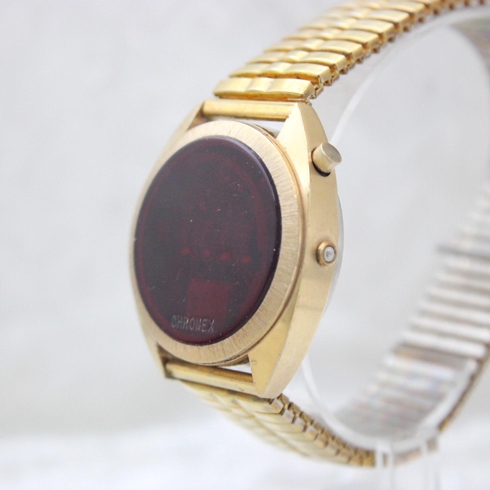 Side profile view of the gold-tone Chronex LED watch, showcasing the oval display and the two control pushers on the right side of the case.