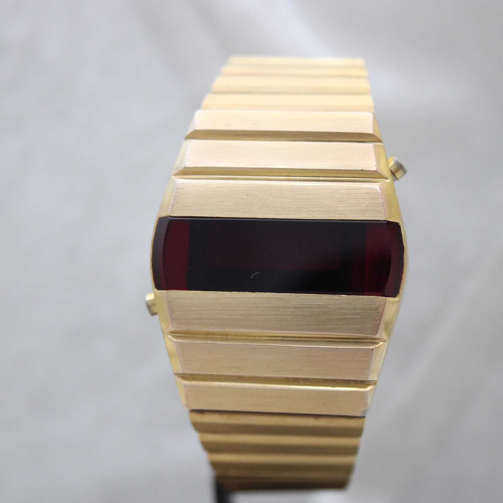 Front-on view of the gold-plated La Générale LED watch with its blank, dark red digital display, presented on a white background.