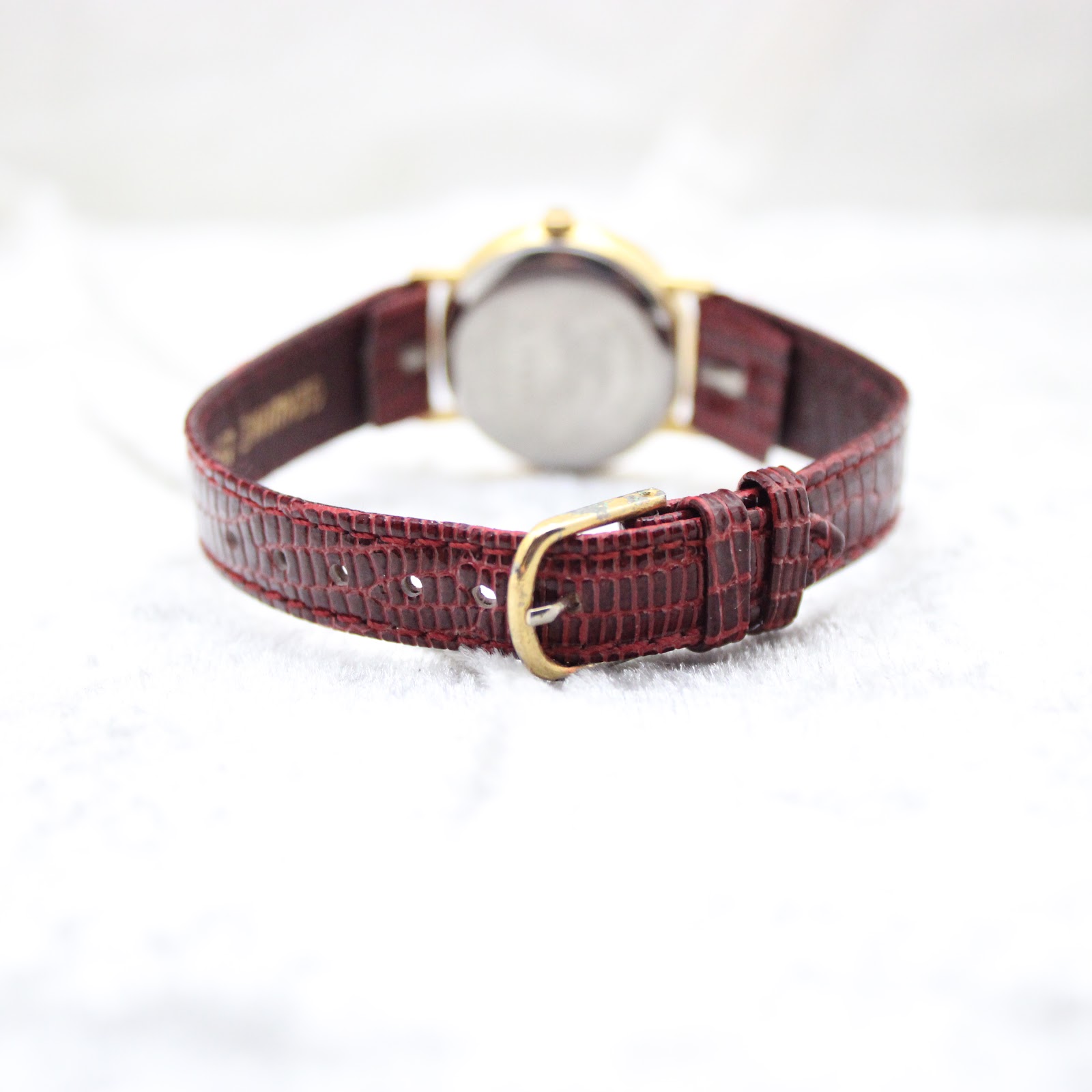 Rear view of the Burberrys watch, showing the burgundy leather strap and gold-tone buckle.