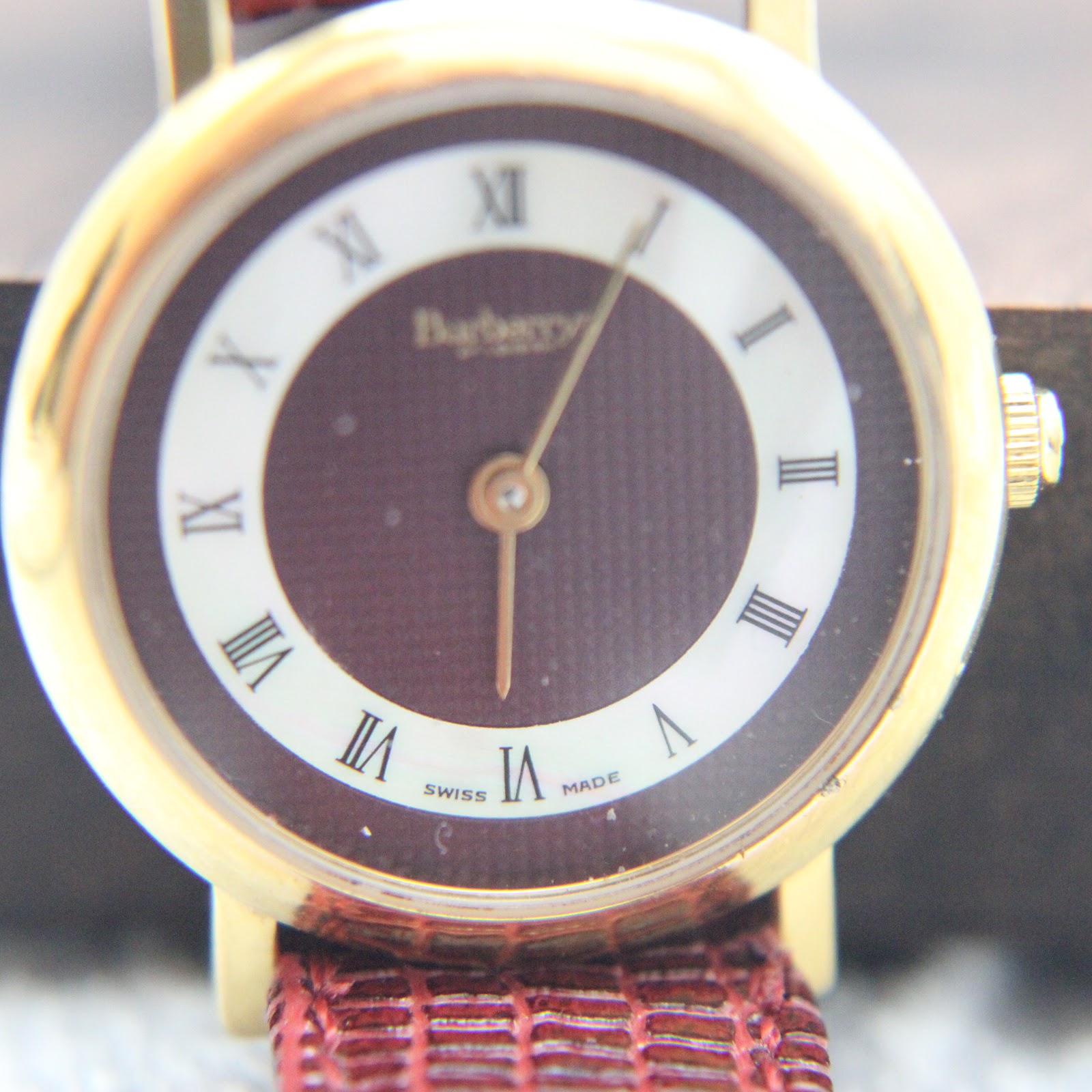 Close-up angled view of the Burberrys dial and gold-tone case, highlighting the mineral glass.
