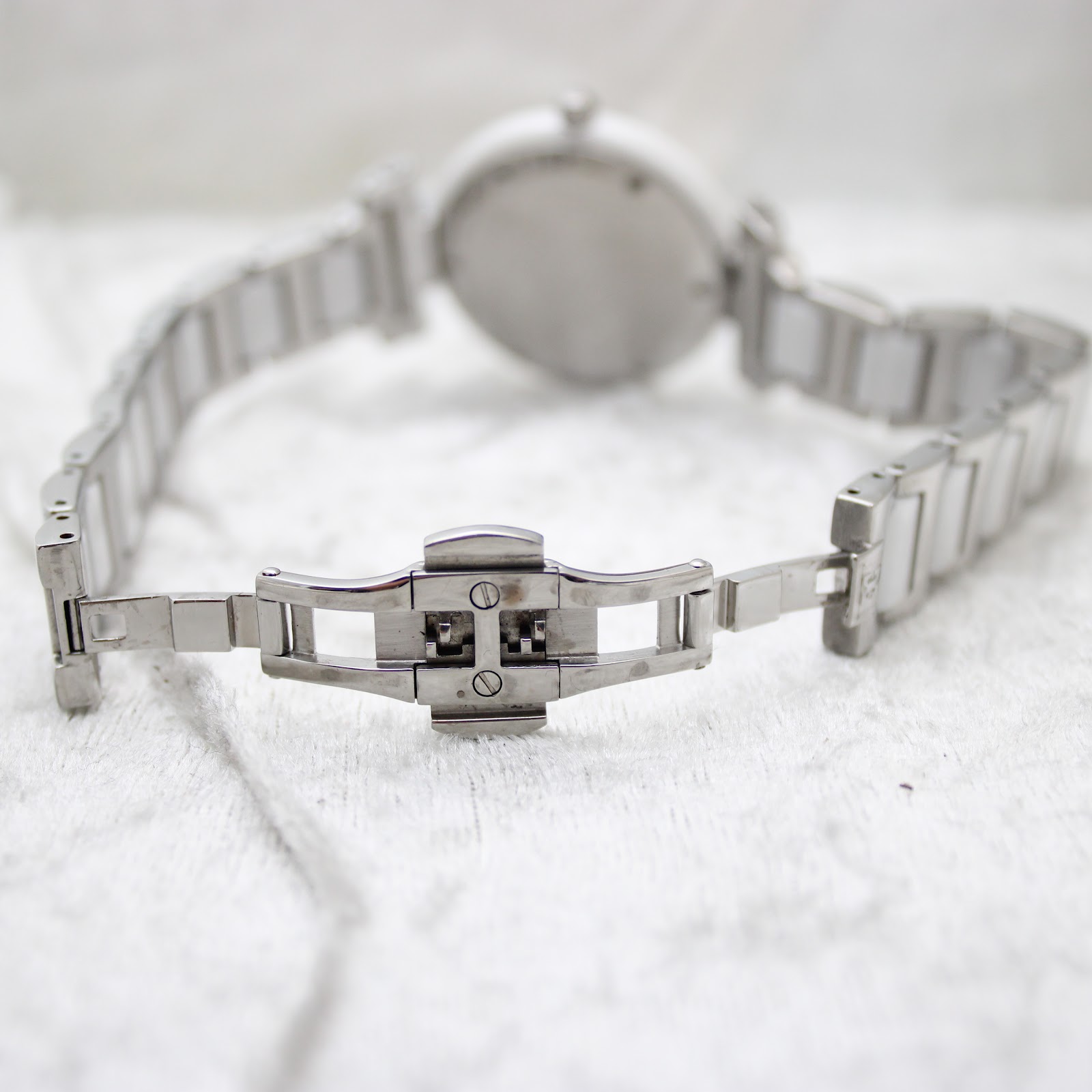 Close-up view of the stainless steel butterfly clasp on the Escada Lauren watch bracelet, opened flat on white fabric.